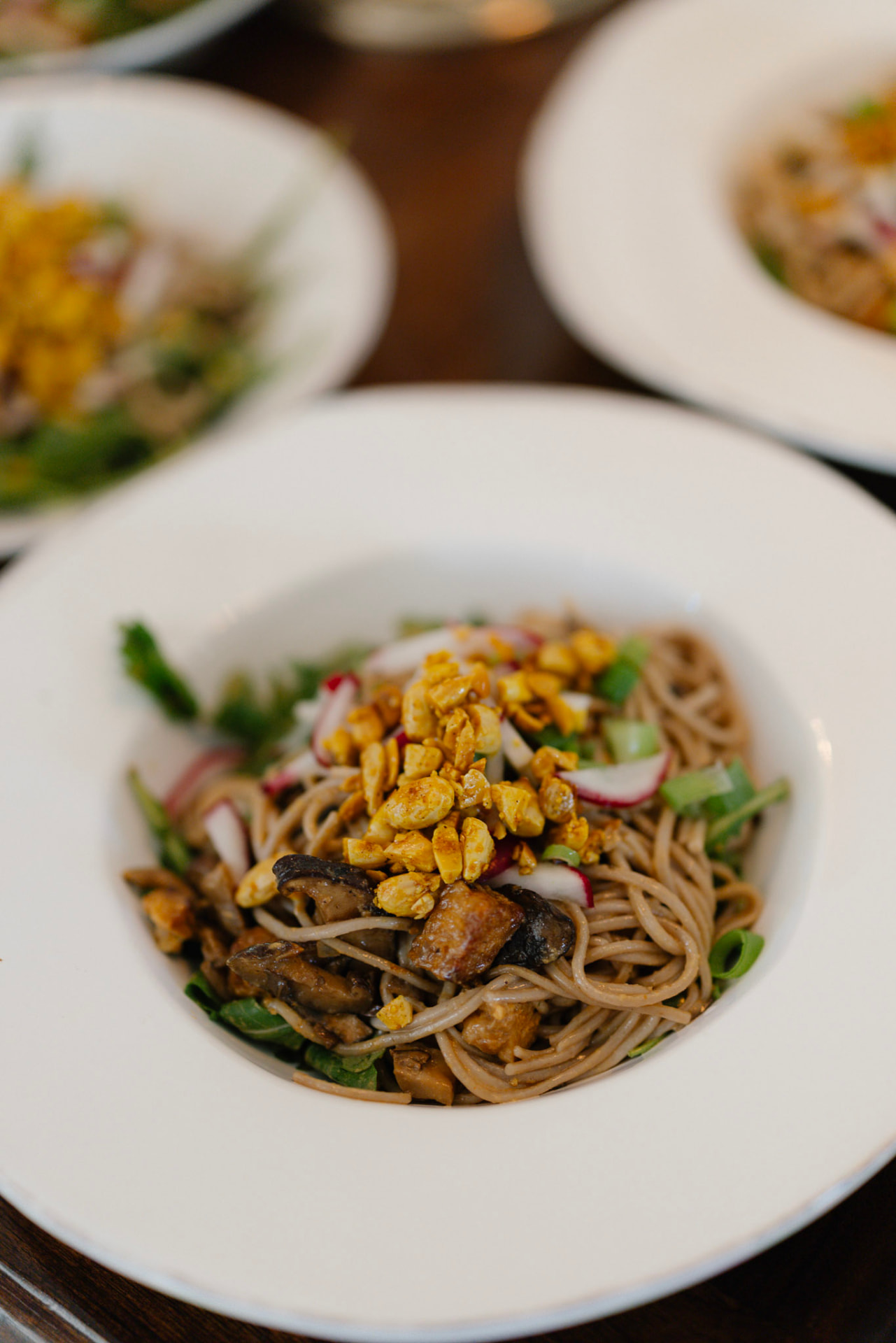 A bowl of soba noodles with mushrooms, radish and toasted peanuts
