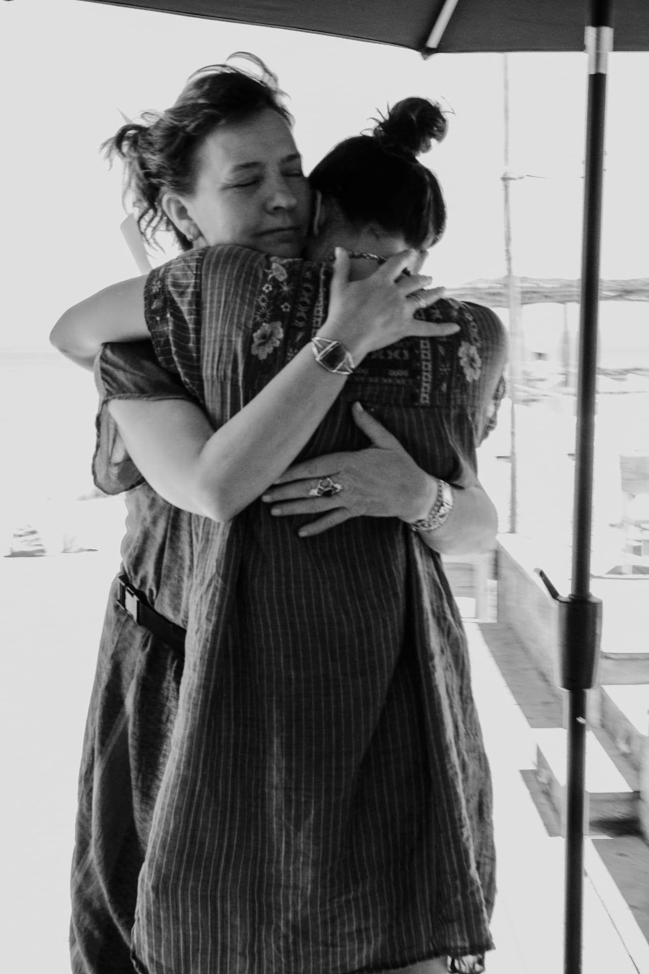 Two women embracing beside an open doorway, in black and white