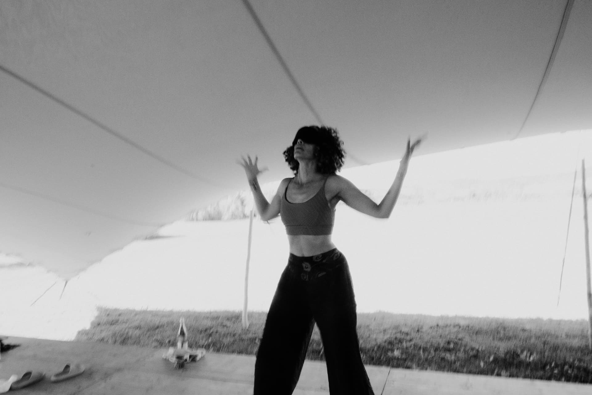 A woman moving with her arms open beneath a canopy, in black and white