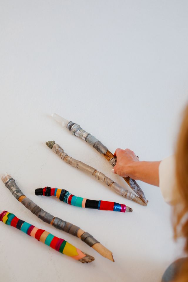 Hand-wrapped wands in bright thread laid out on white, Baja