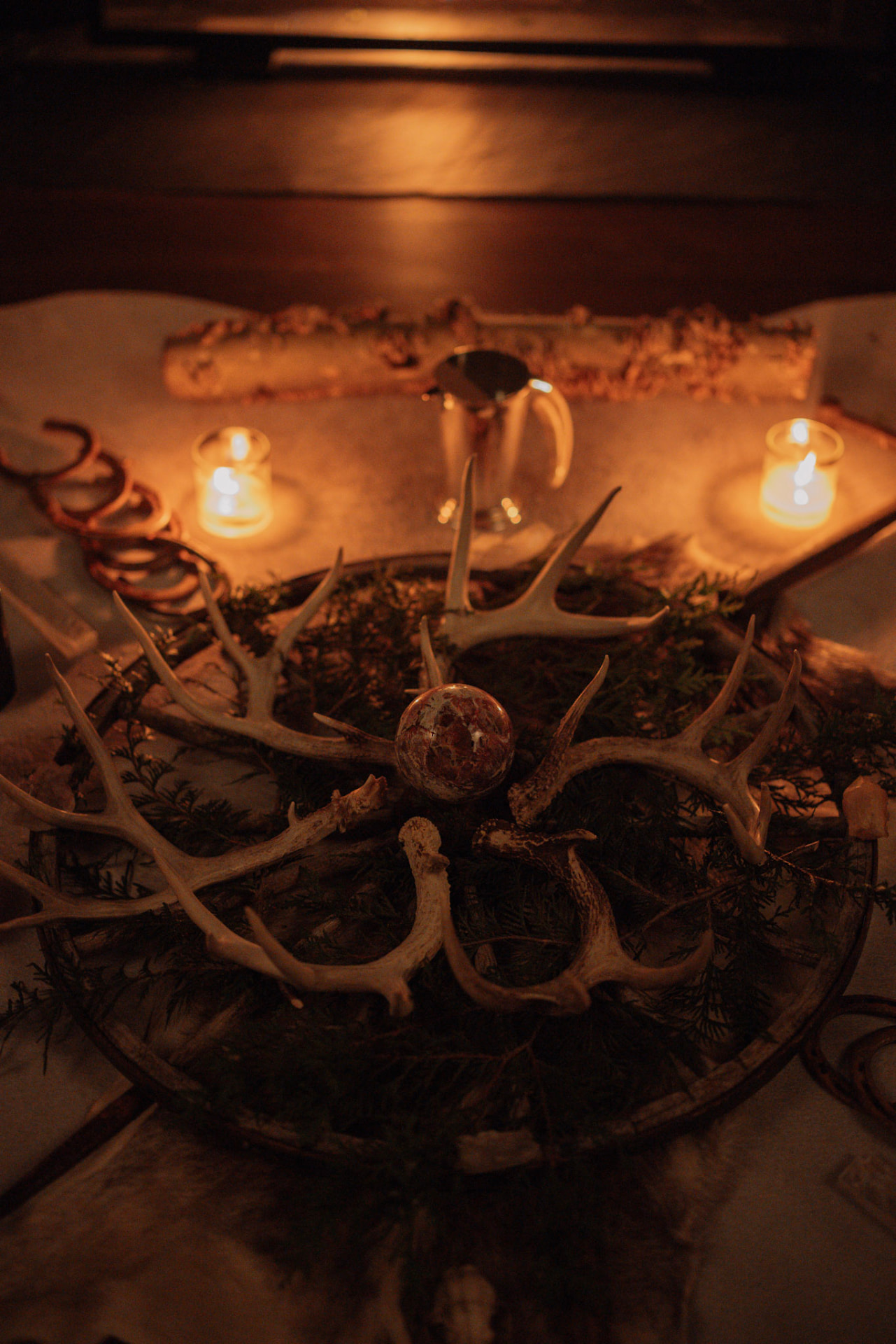 Antlers, greenery and gathered objects arranged by candlelight