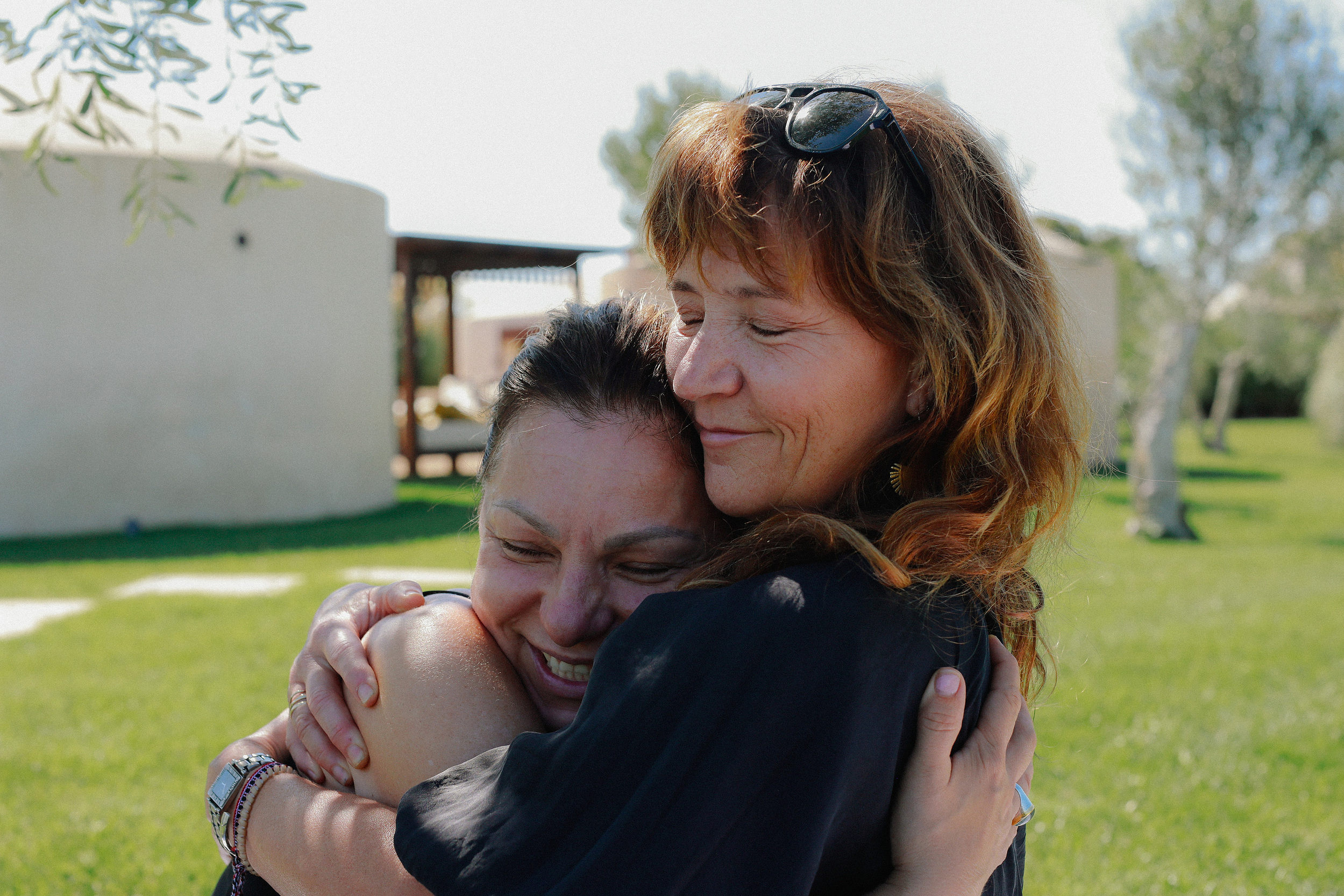 Two women embracing and laughing on the grass