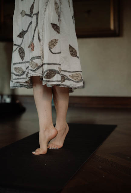 Bare feet lifting from a mat beneath a botanical patterned dress