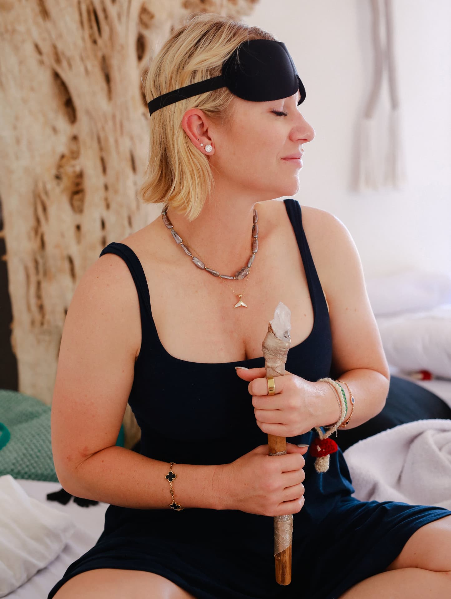 A woman with a sleep mask lifted, holding a crystal wand