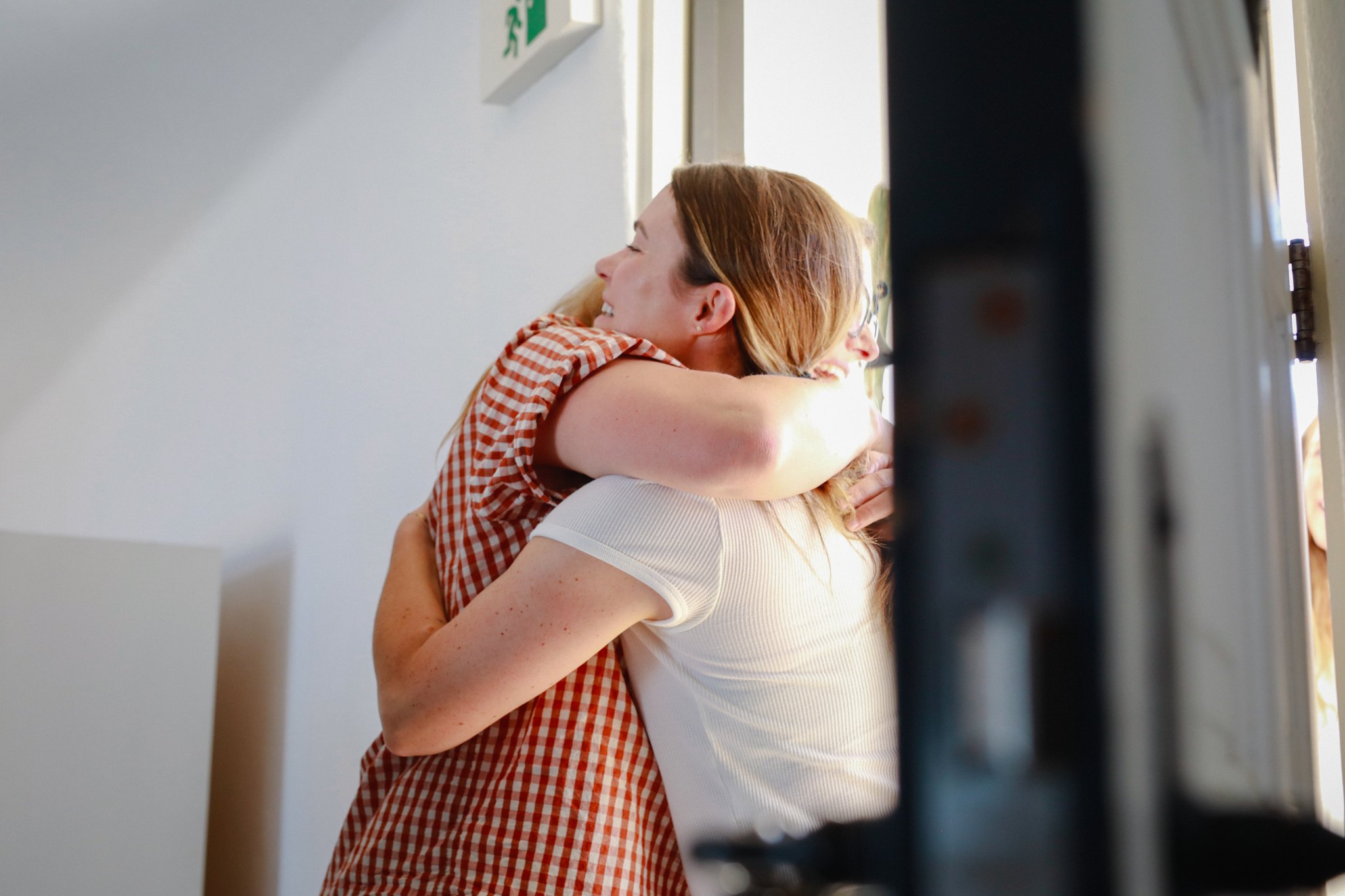 Two women embracing warmly beside a doorway