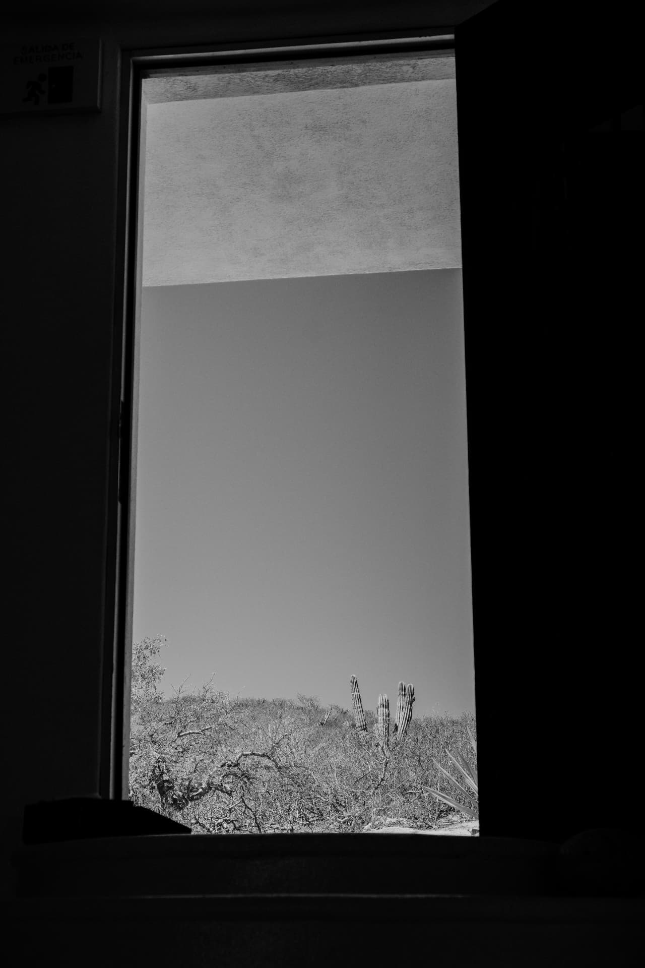 The sea and desert framed by a dark doorway, in black and white