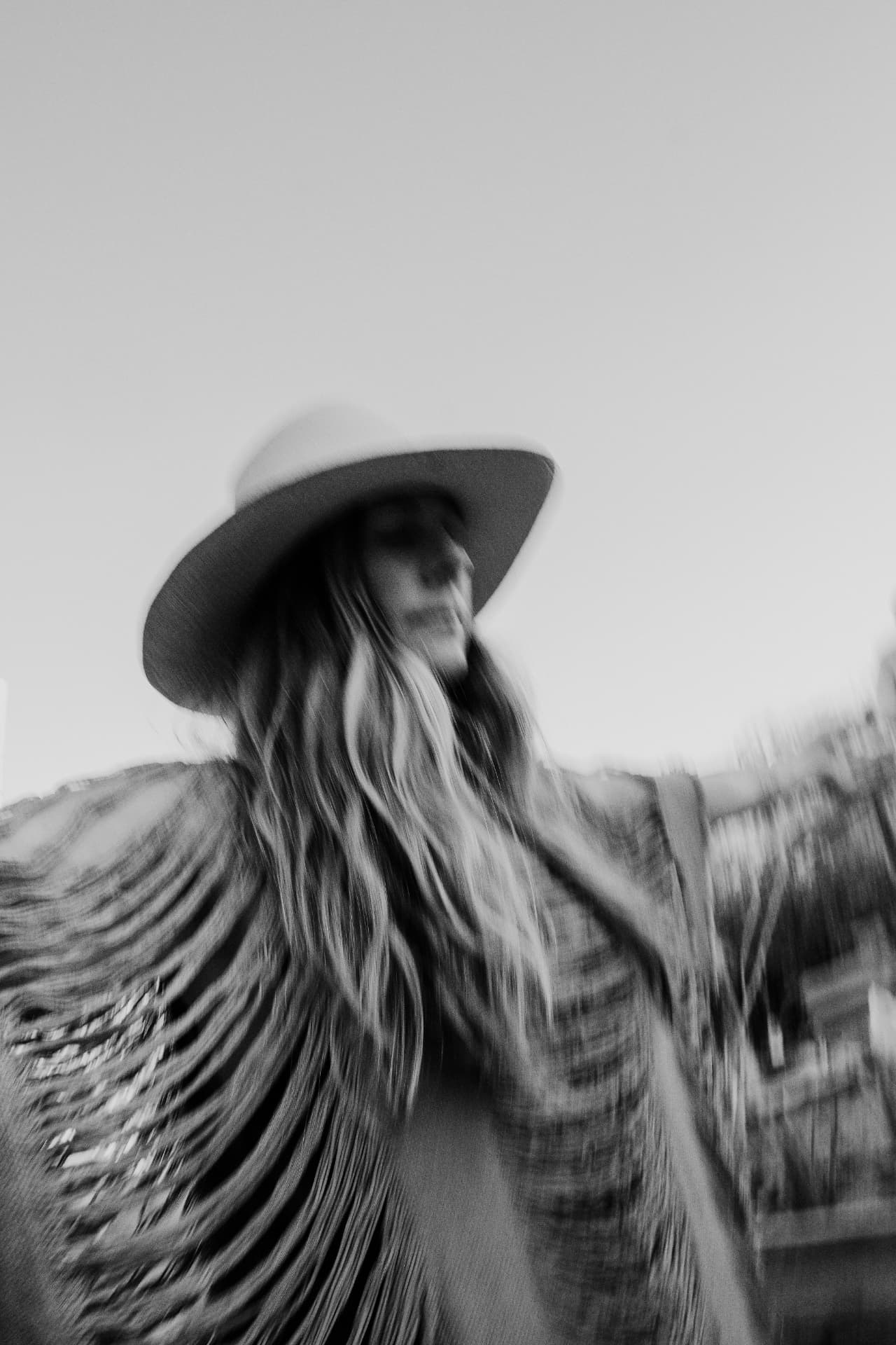 A woman in a wide-brimmed hat holding a feather fan, in black and white