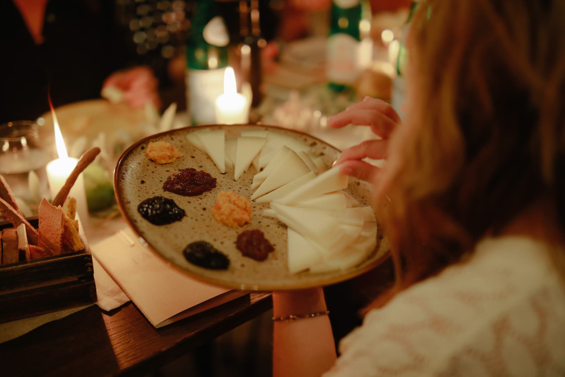 A plate of cheese and preserves passed by candlelight