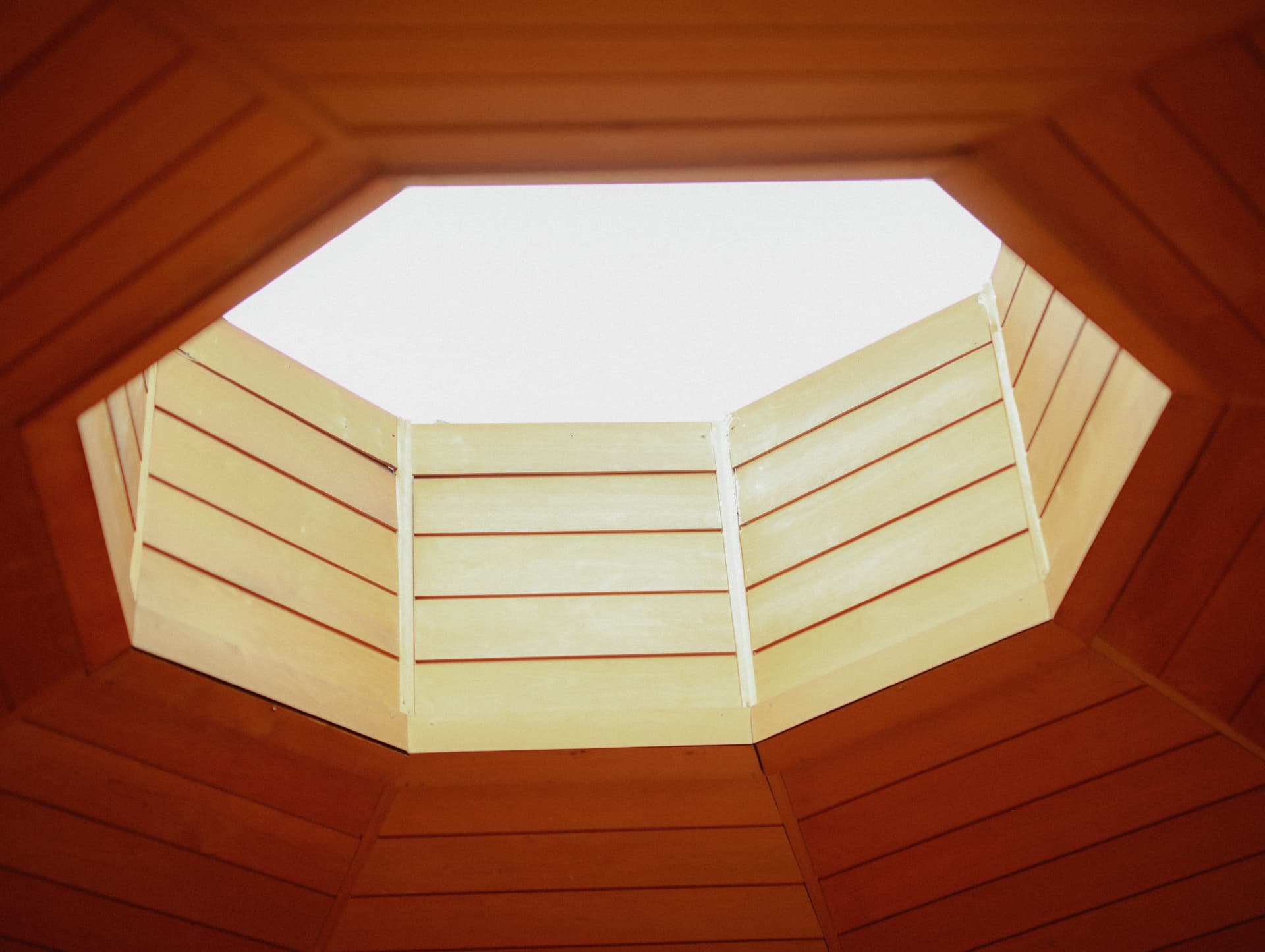 A geometric skylight framed by warm wooden ceiling panels