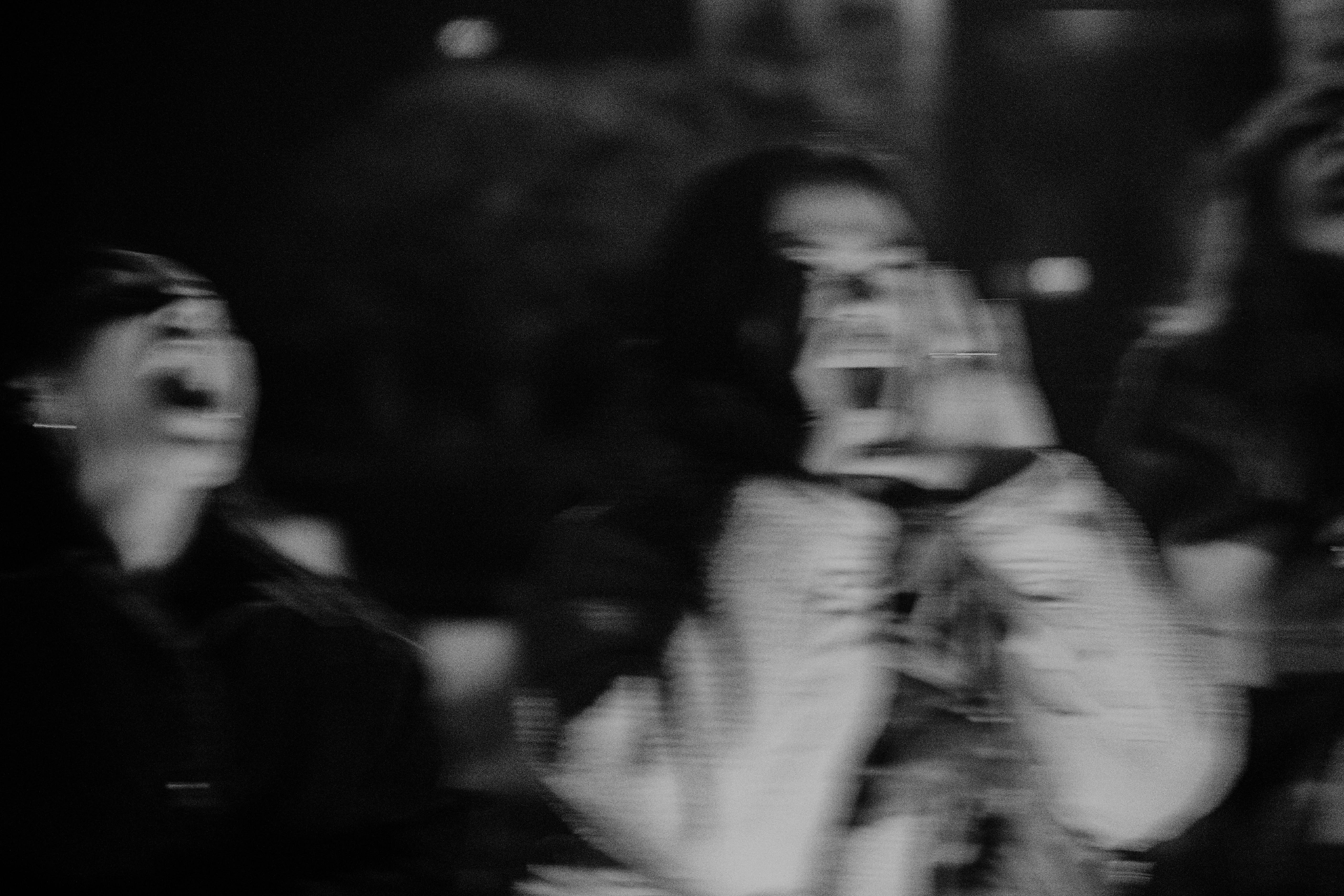 A grainy black and white photograph of women calling out together, their gestures blurred with movement