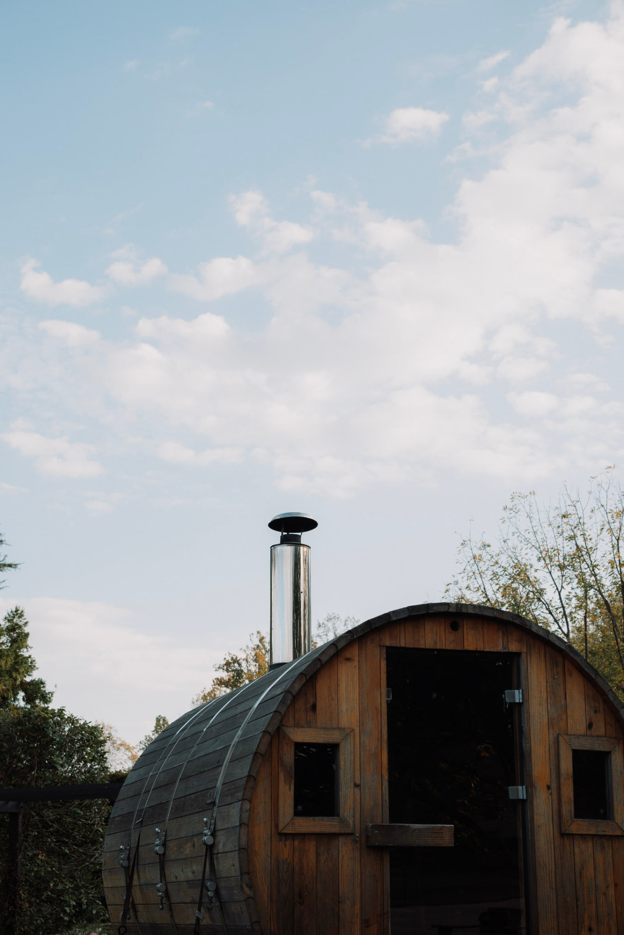 A wooden barrel sauna beneath a pale blue sky in Virginia