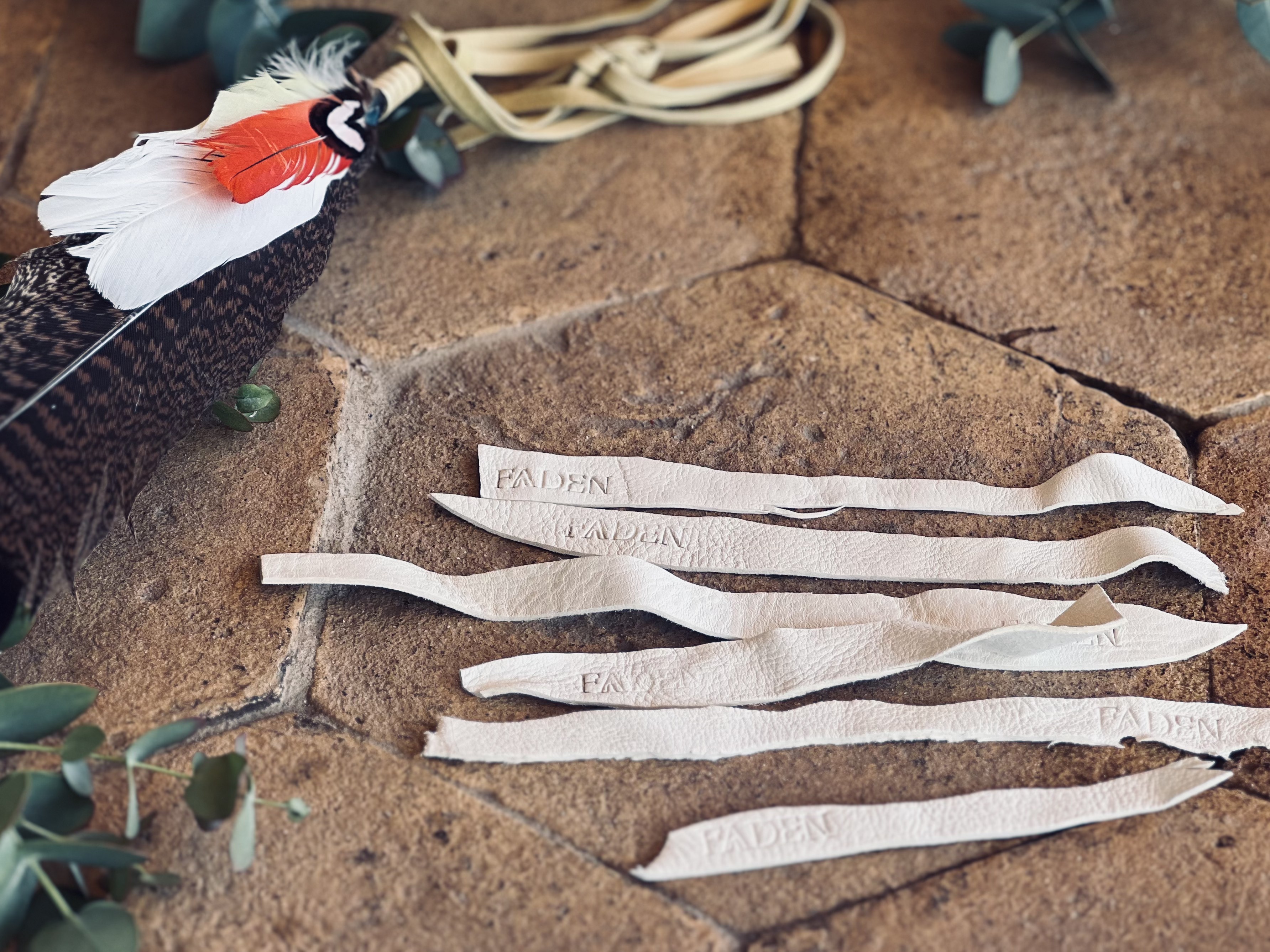 FADEN embossed leather ribbons and red, white and patterned feathers on stone
