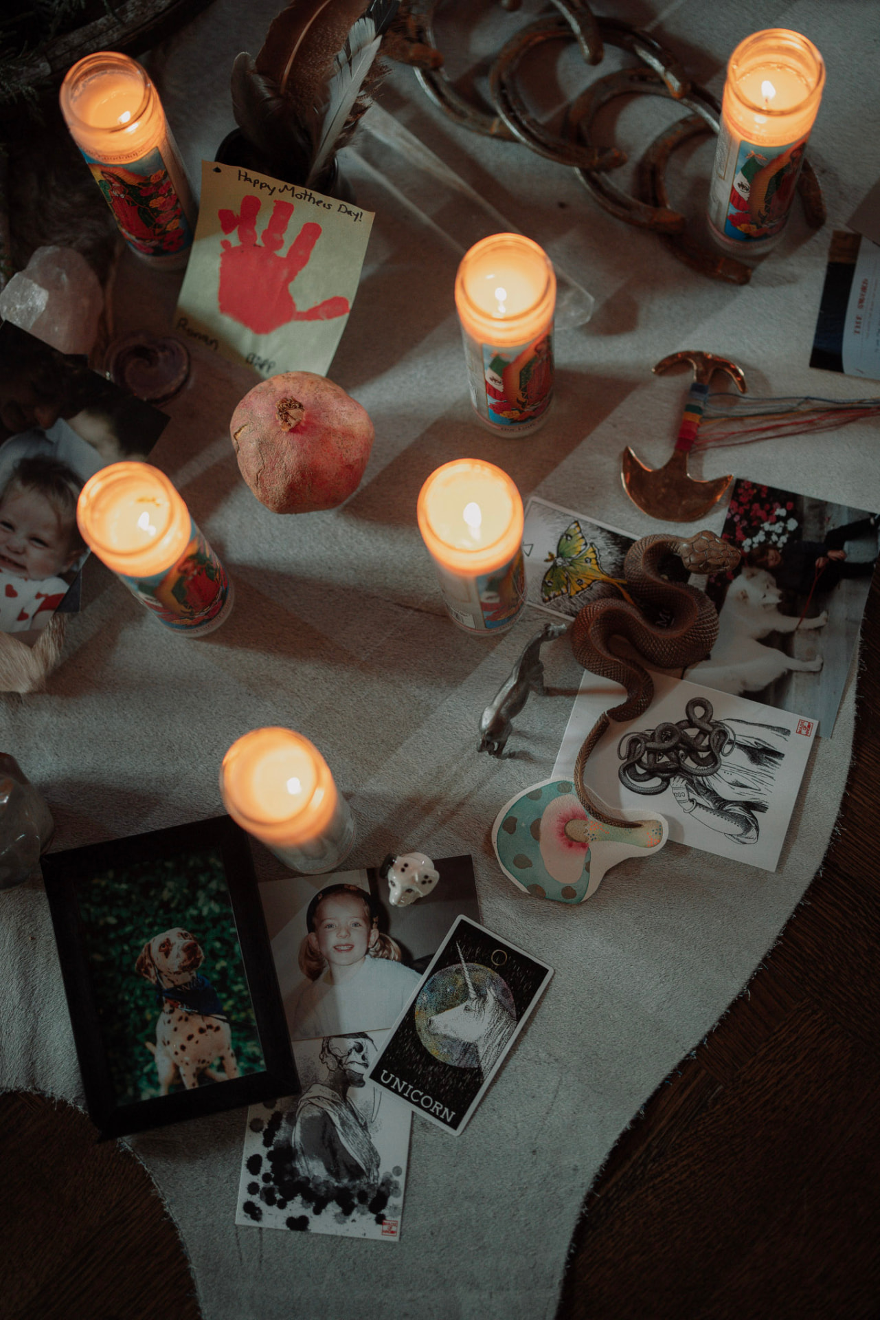 Candles, photographs, cards, a pomegranate and keepsakes gathered on an altar