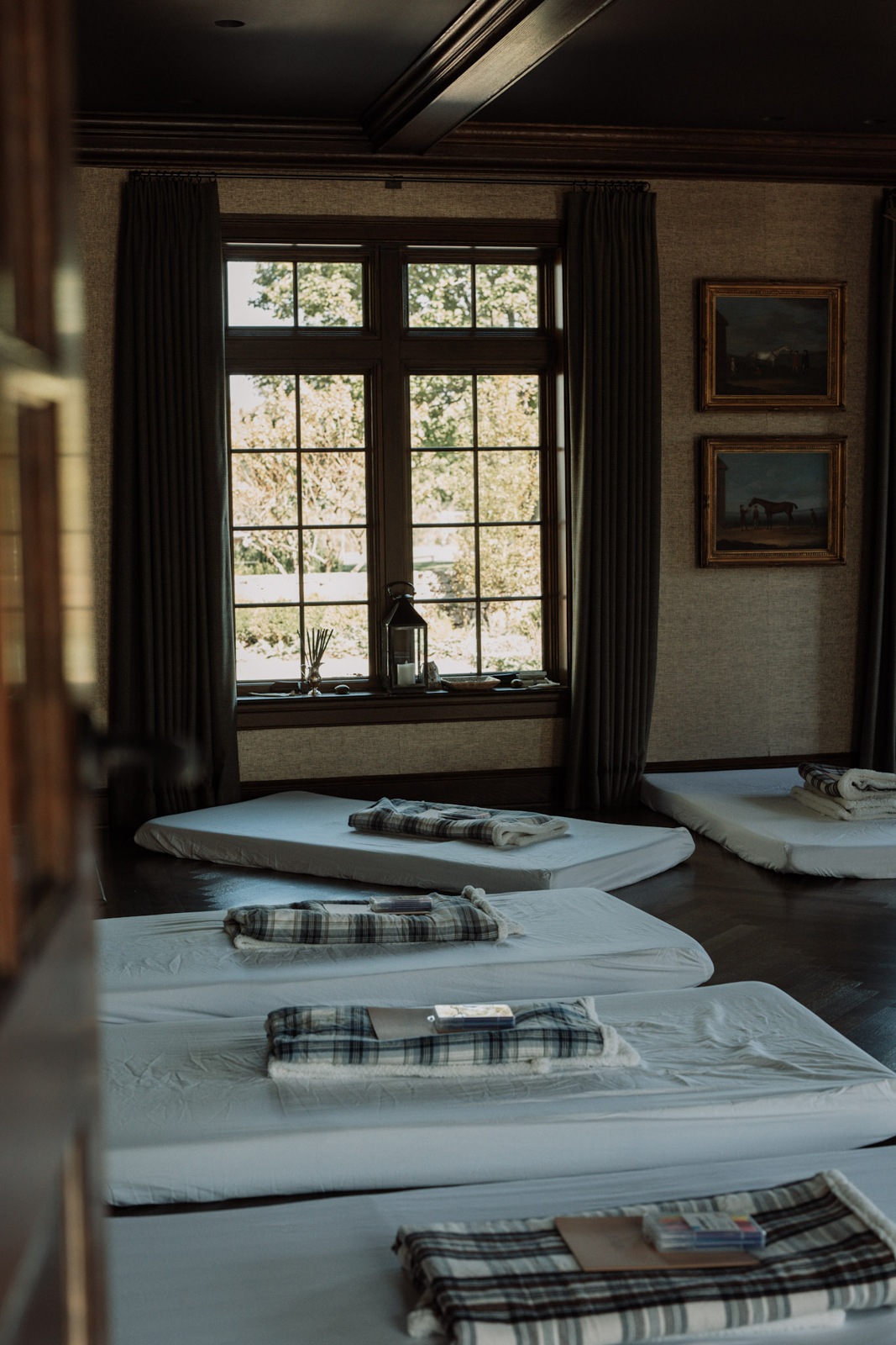 Mattresses and plaid blankets laid out beneath tall windows
