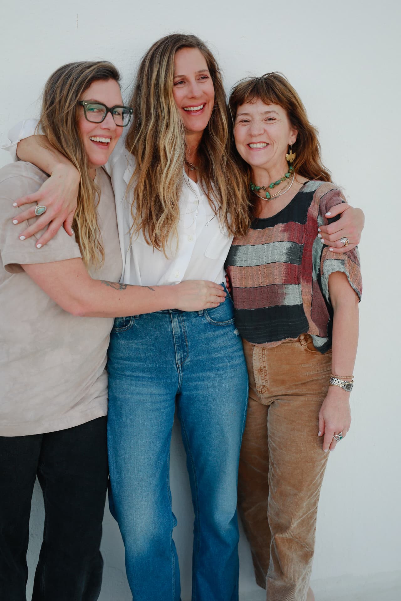 Three women laughing with their arms around one another