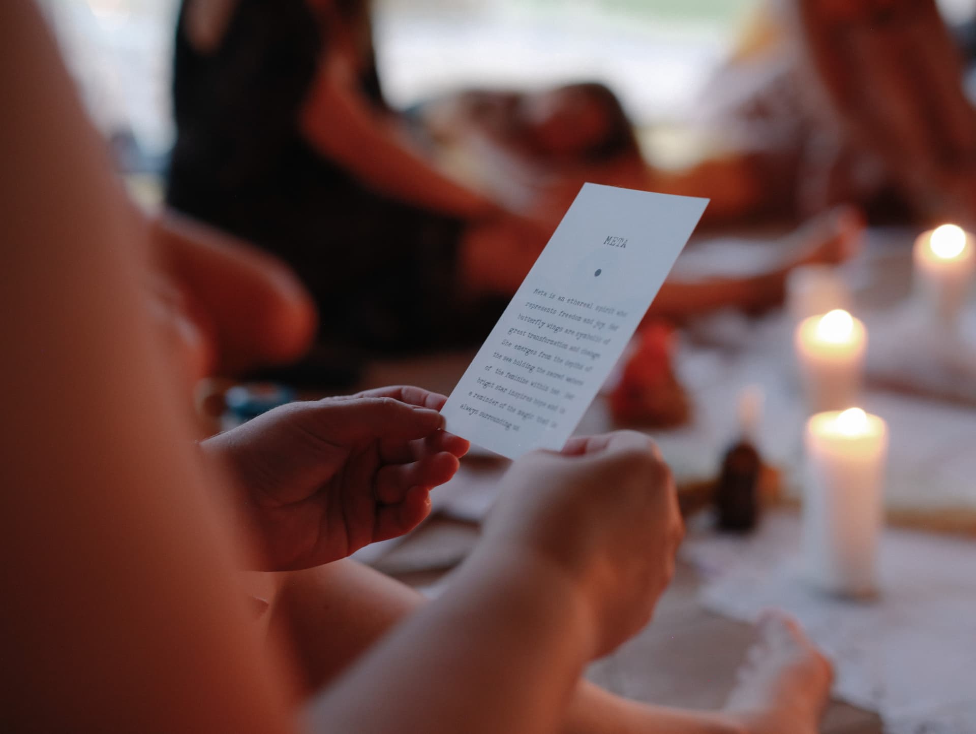 A woman reading a small handwritten card by candlelight