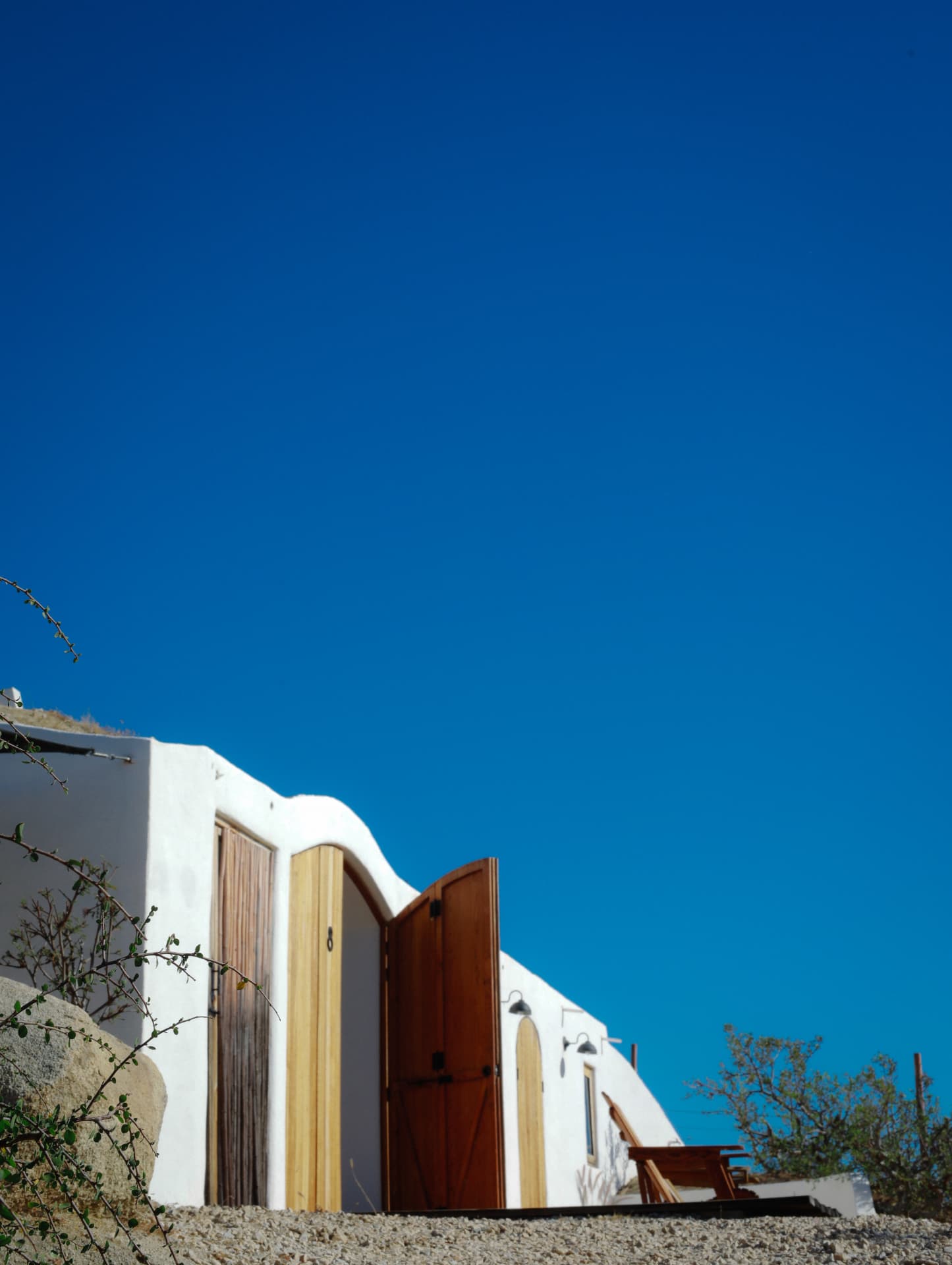 White curved buildings and wooden doors beneath a clear blue Baja sky