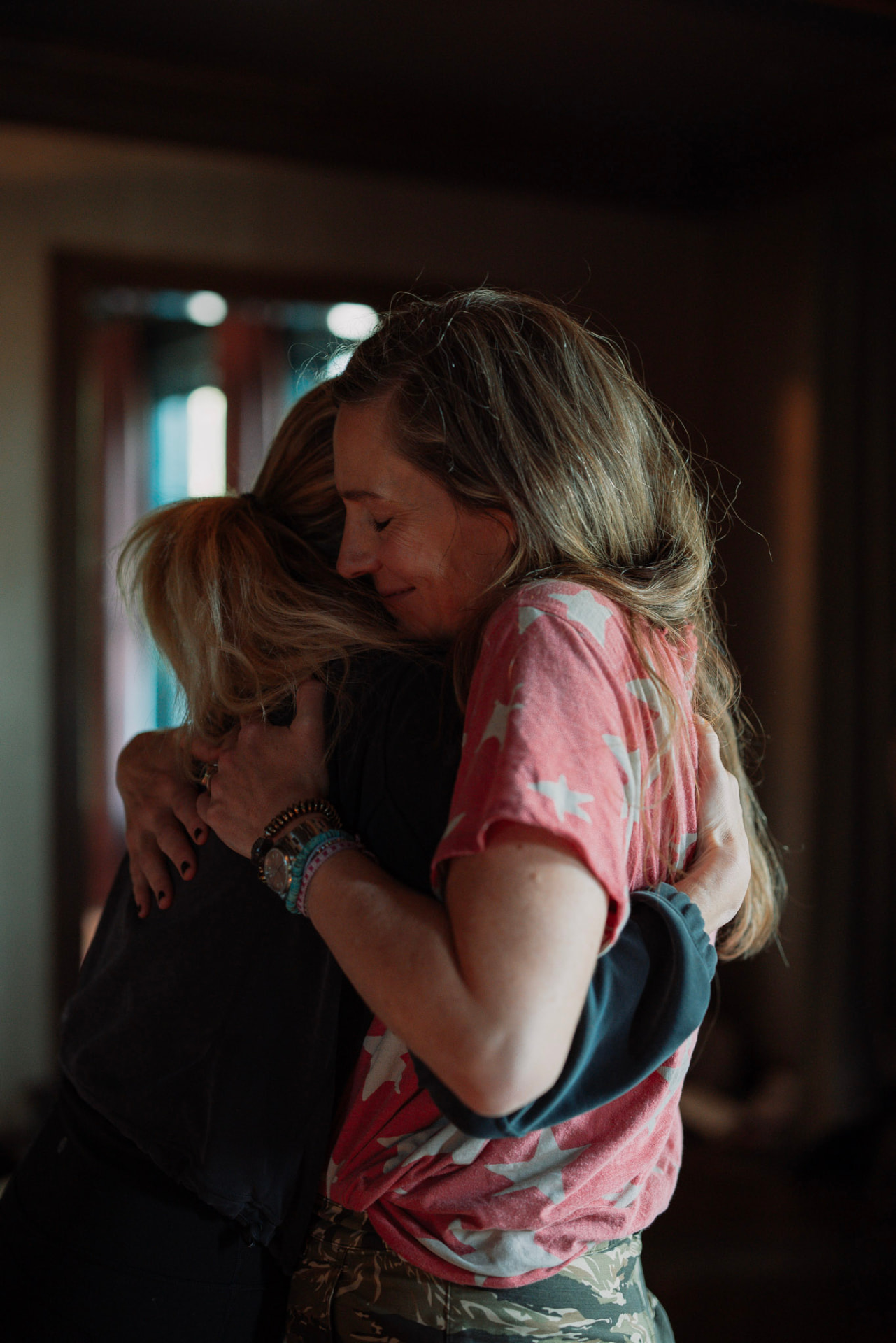 Two women sharing a long embrace in a softly lit room