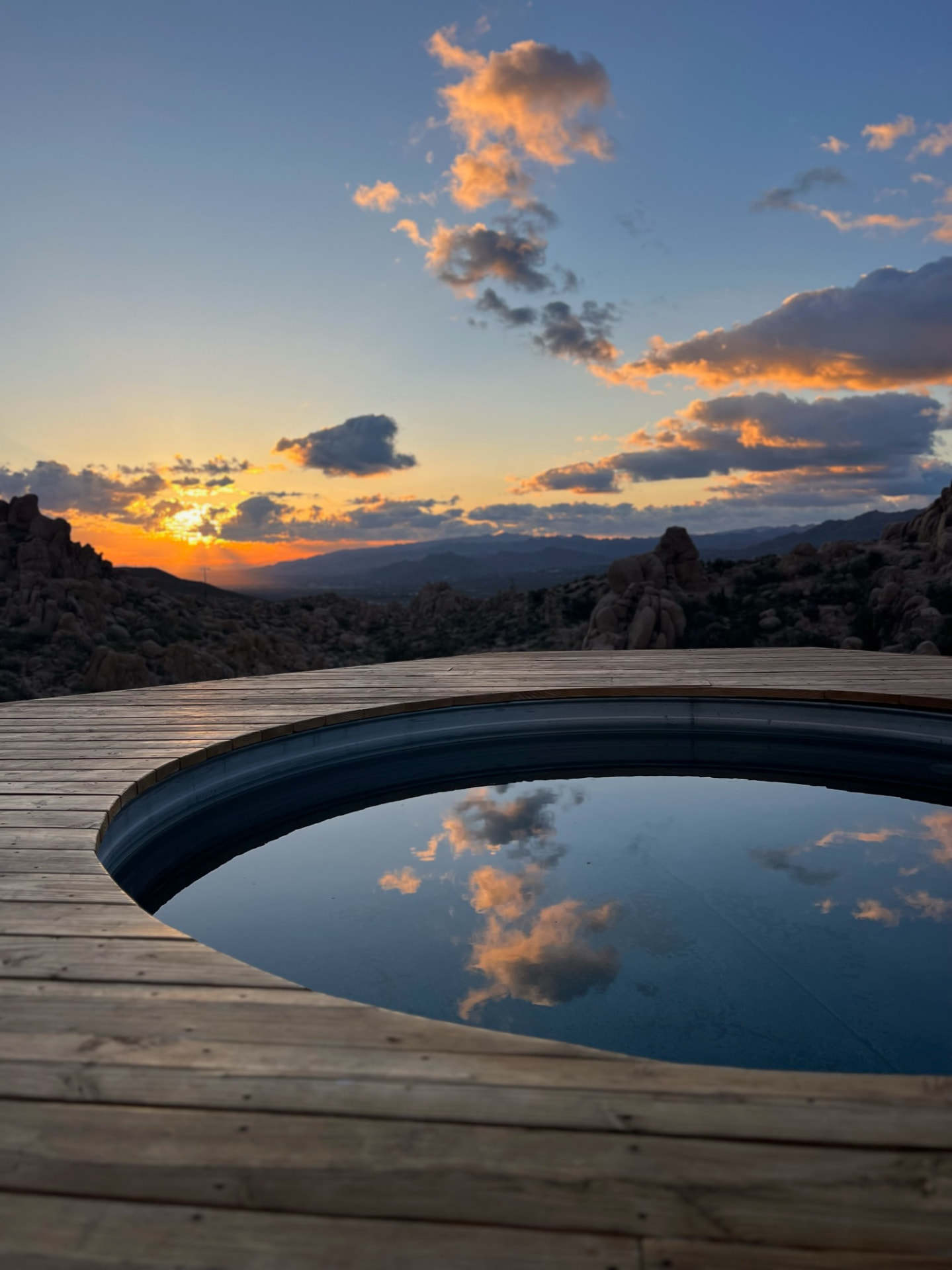 Sunset clouds reflected in a round pool on the desert deck
