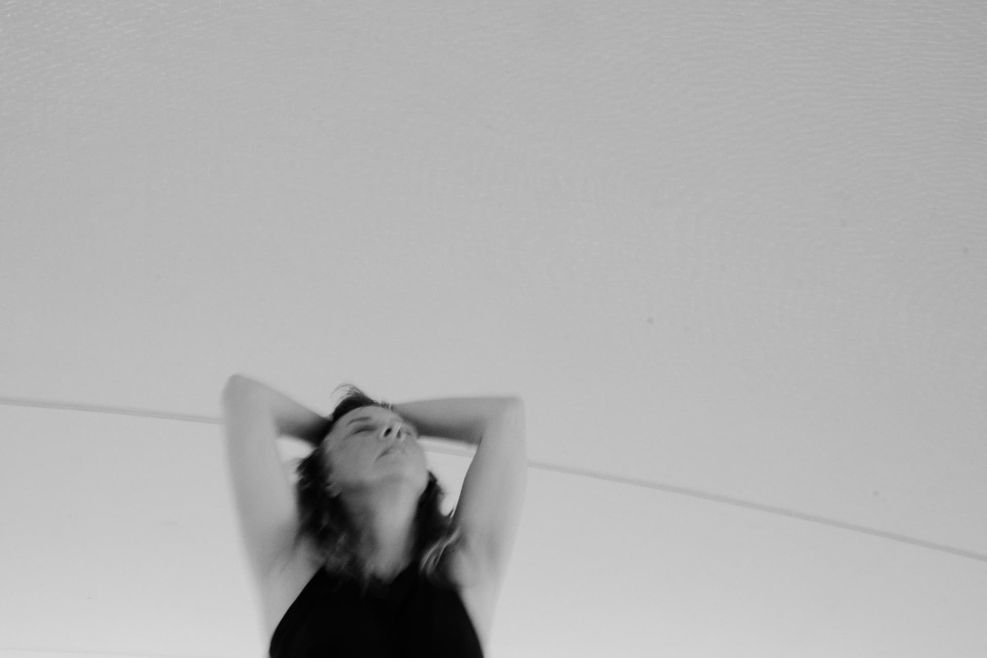 A woman leaning back with her hands behind her head, in black and white