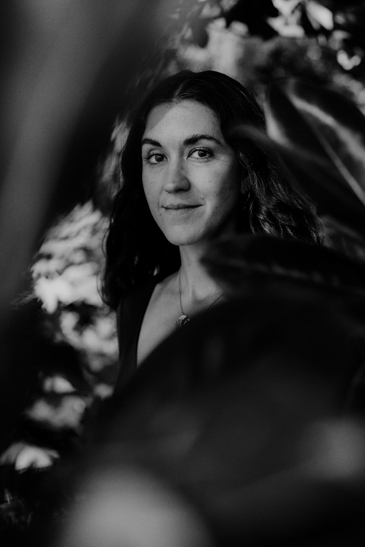 Black-and-white portrait of Marcela framed by dark leaves