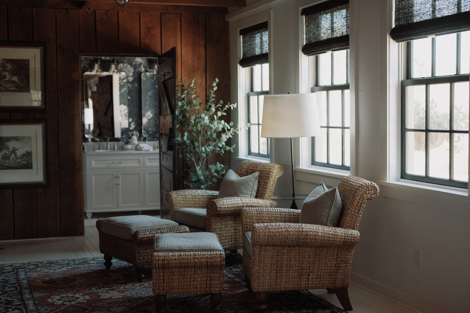 Wicker armchairs by tall windows in a wood panelled room