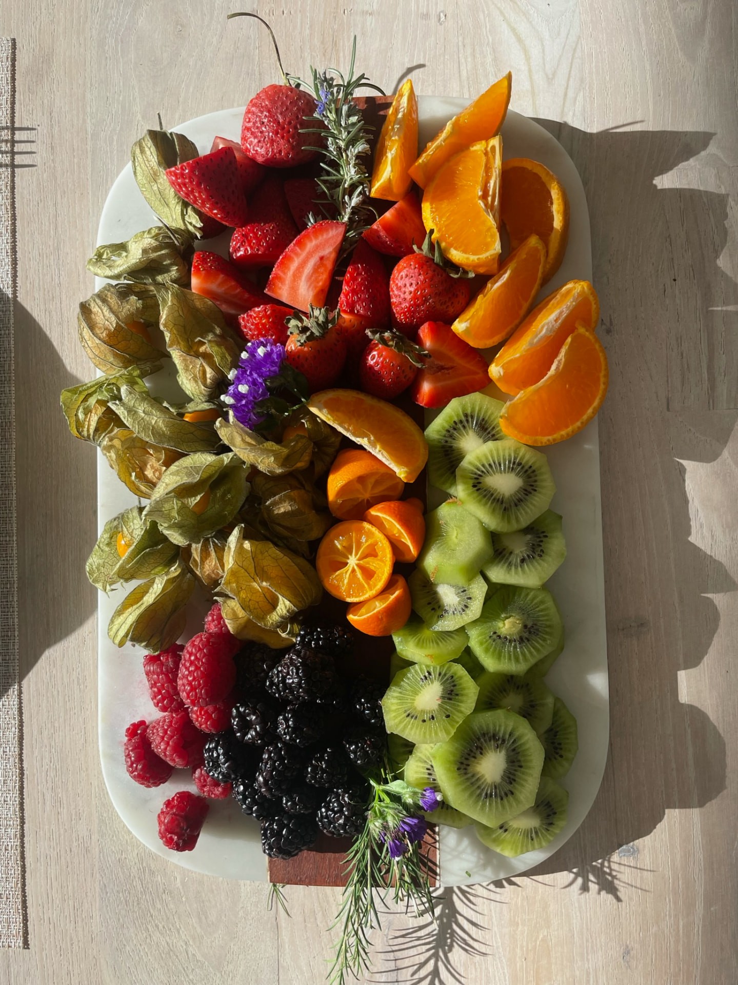 A platter of berries, citrus and grapes arranged with flowers