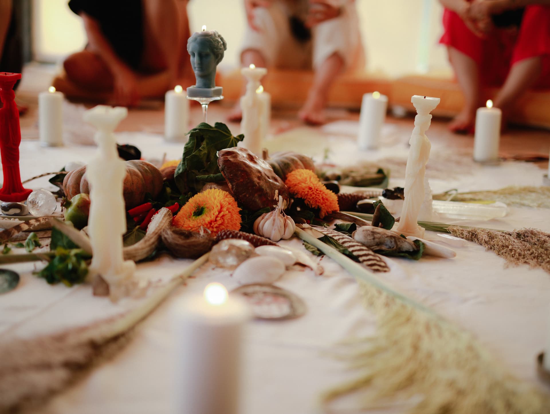 An altar of candles, flowers, shells and small figures laid on the floor