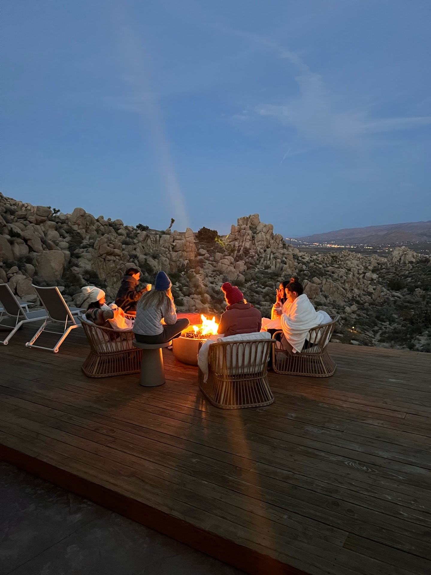 Women seated around a glowing fire on the desert deck at twilight