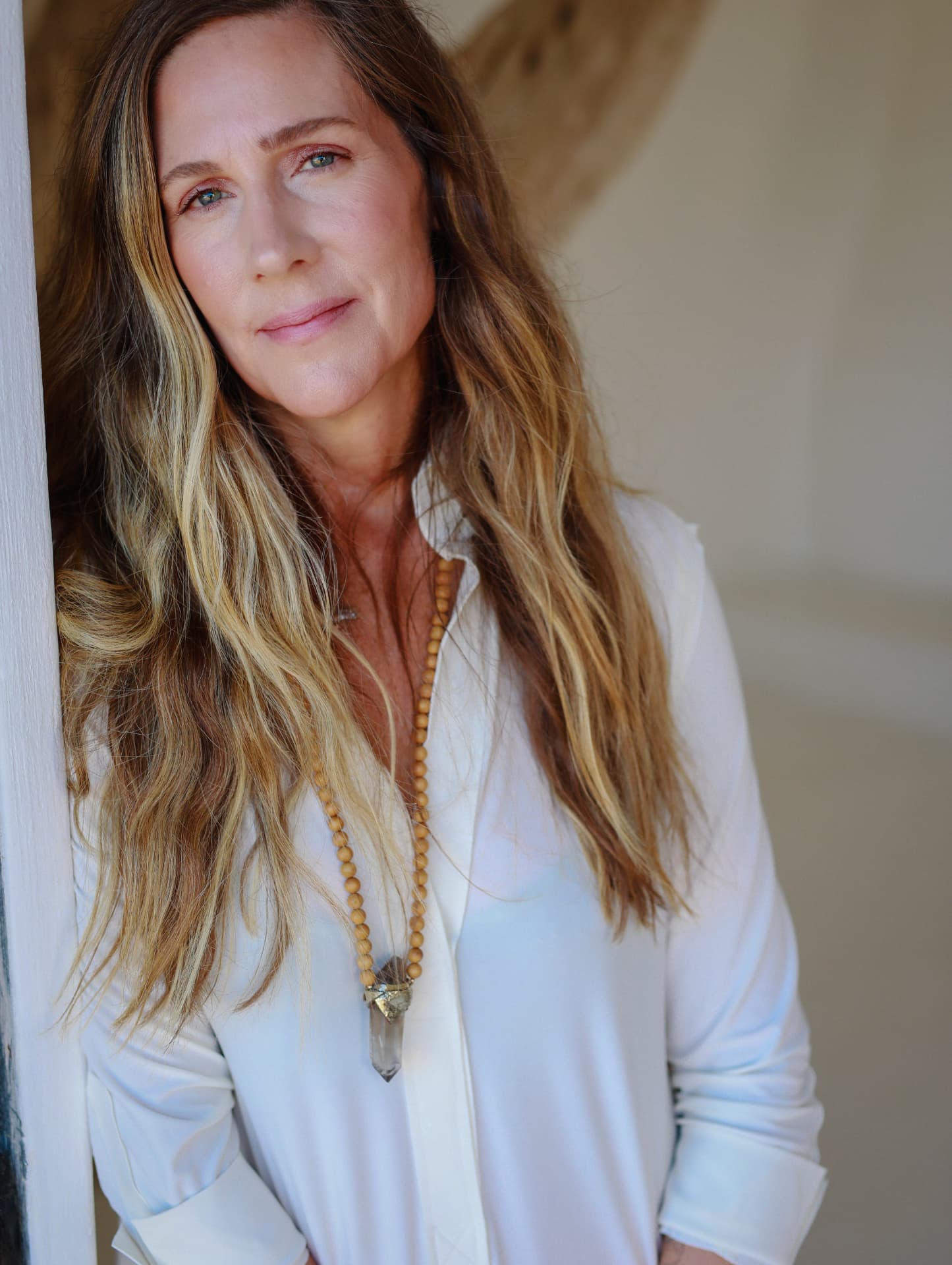 Lindsay Olshan in a white blouse, leaning beside a doorway