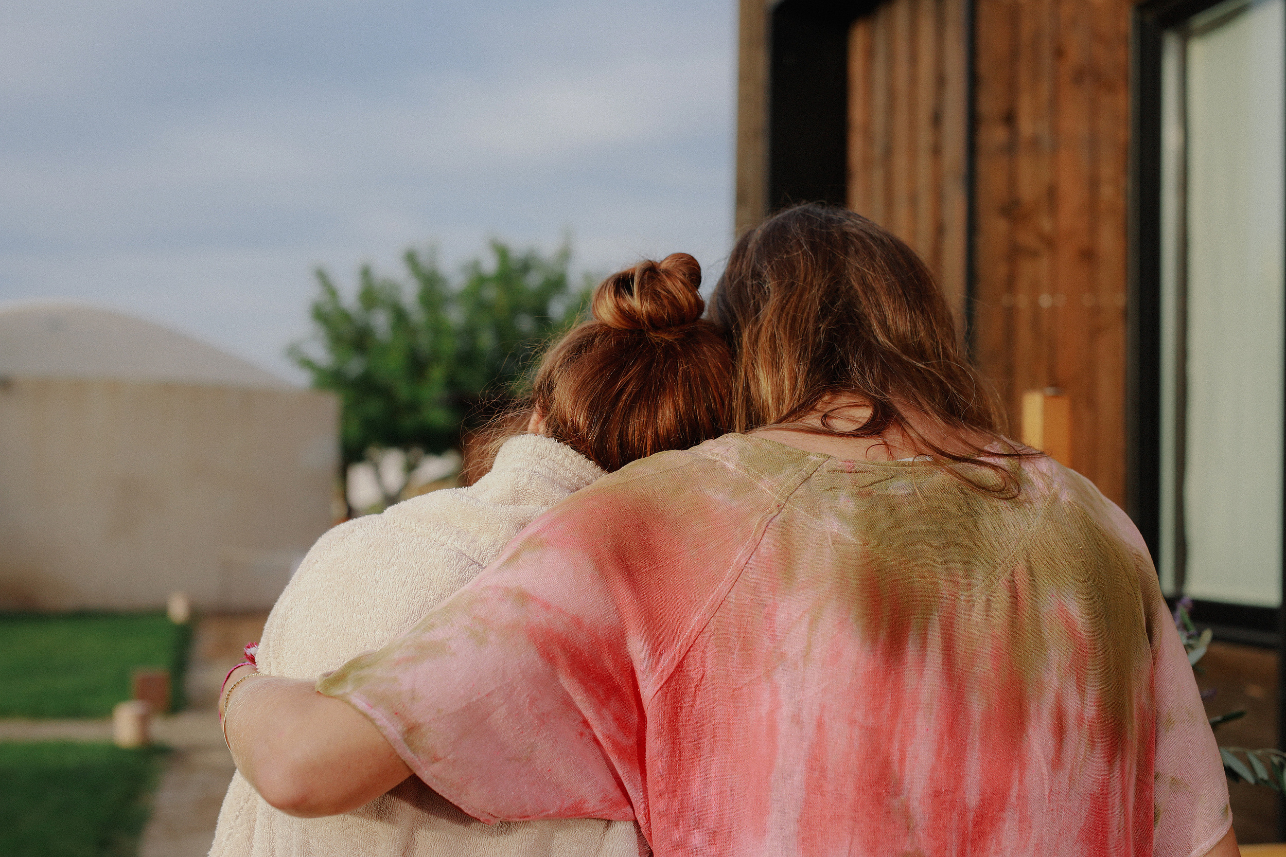 Two women holding each other in a long embrace outdoors
