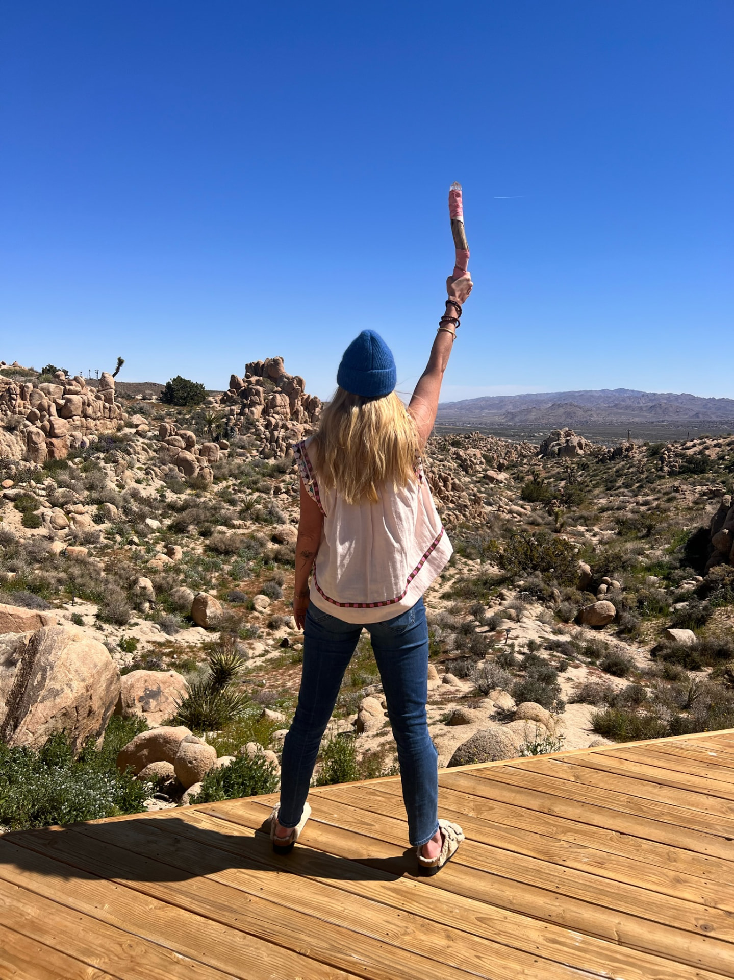 A woman standing on the desert deck with one arm raised