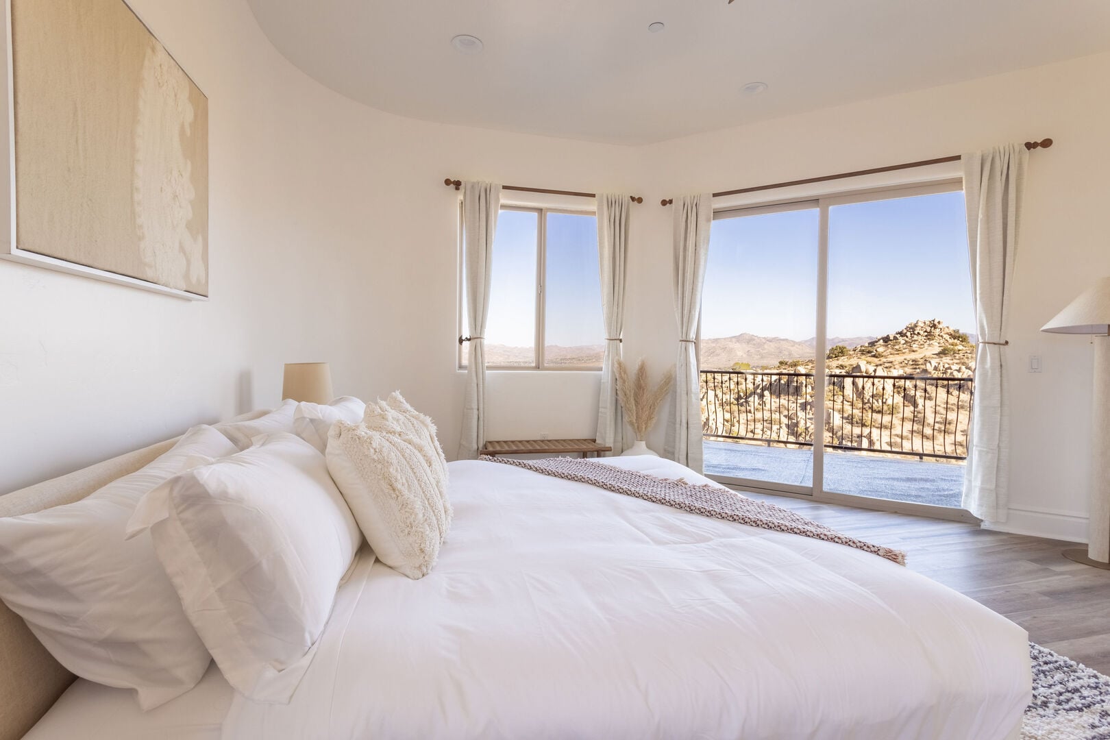 A bedroom with white linen and glass doors facing the boulders and balcony