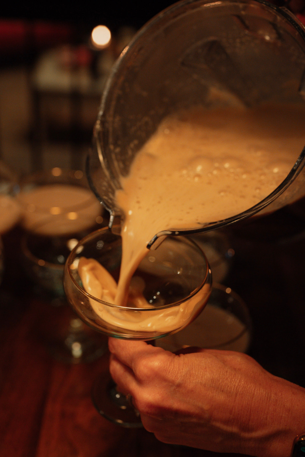 A kava White Russian poured from a glass pitcher by candlelight