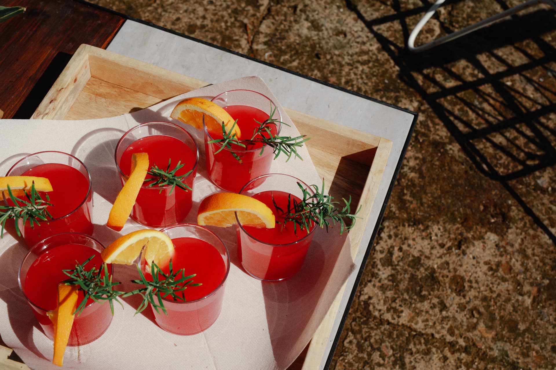 Glasses of blood orange spritz with rosemary on a wooden tray