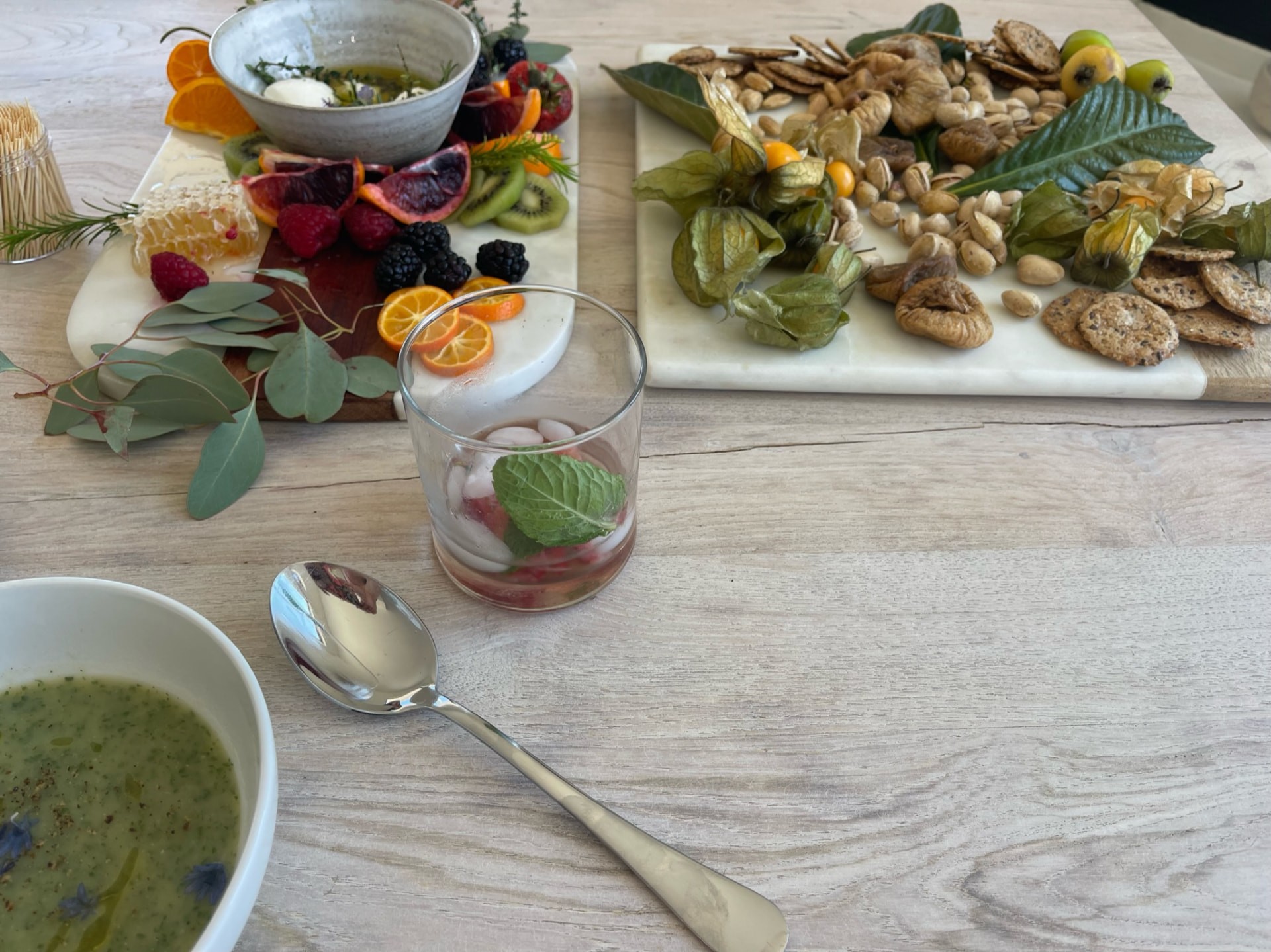 Bowls and platters of food with flowers and leafy garnishes on a pale table