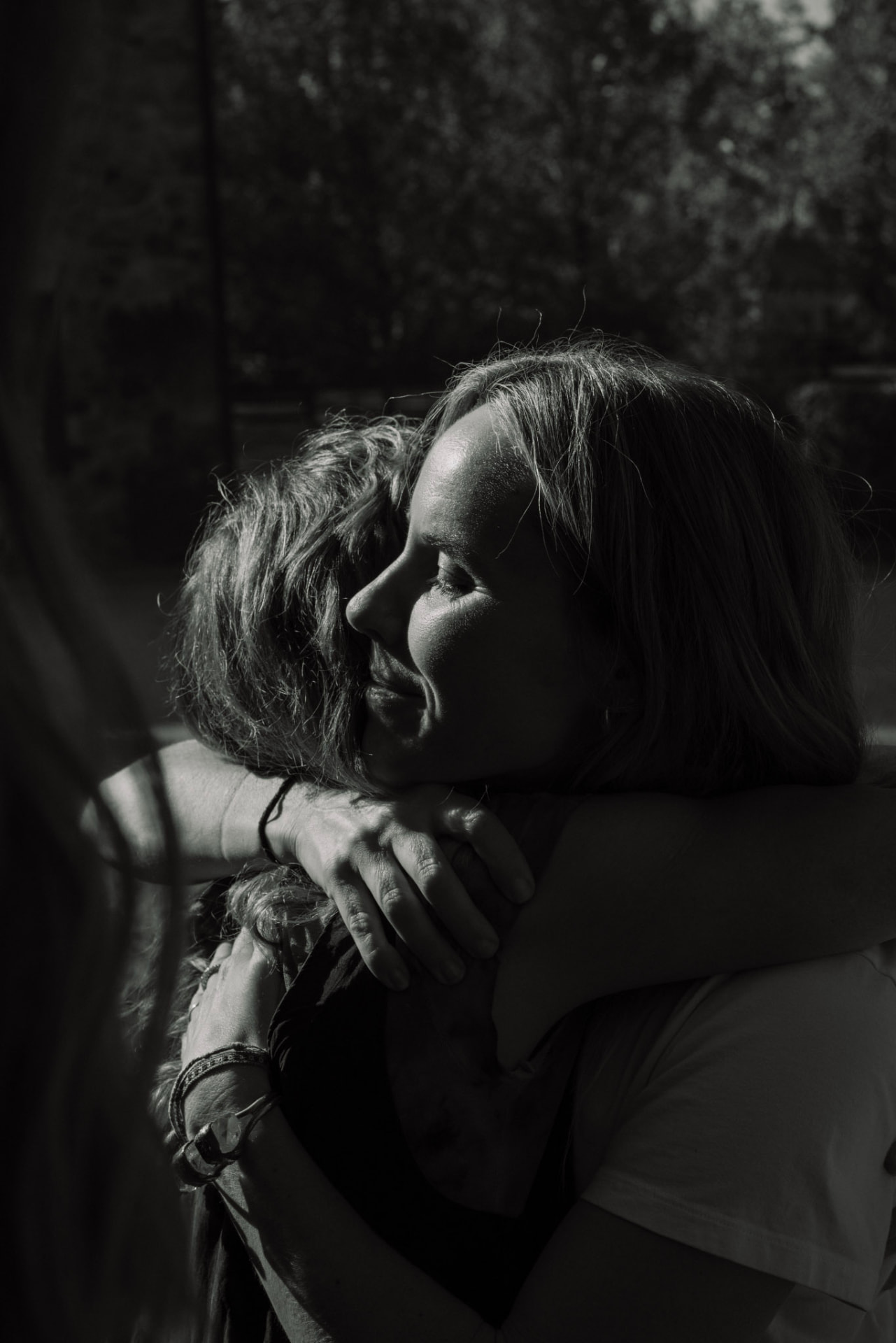Two women holding each other close, in black and white