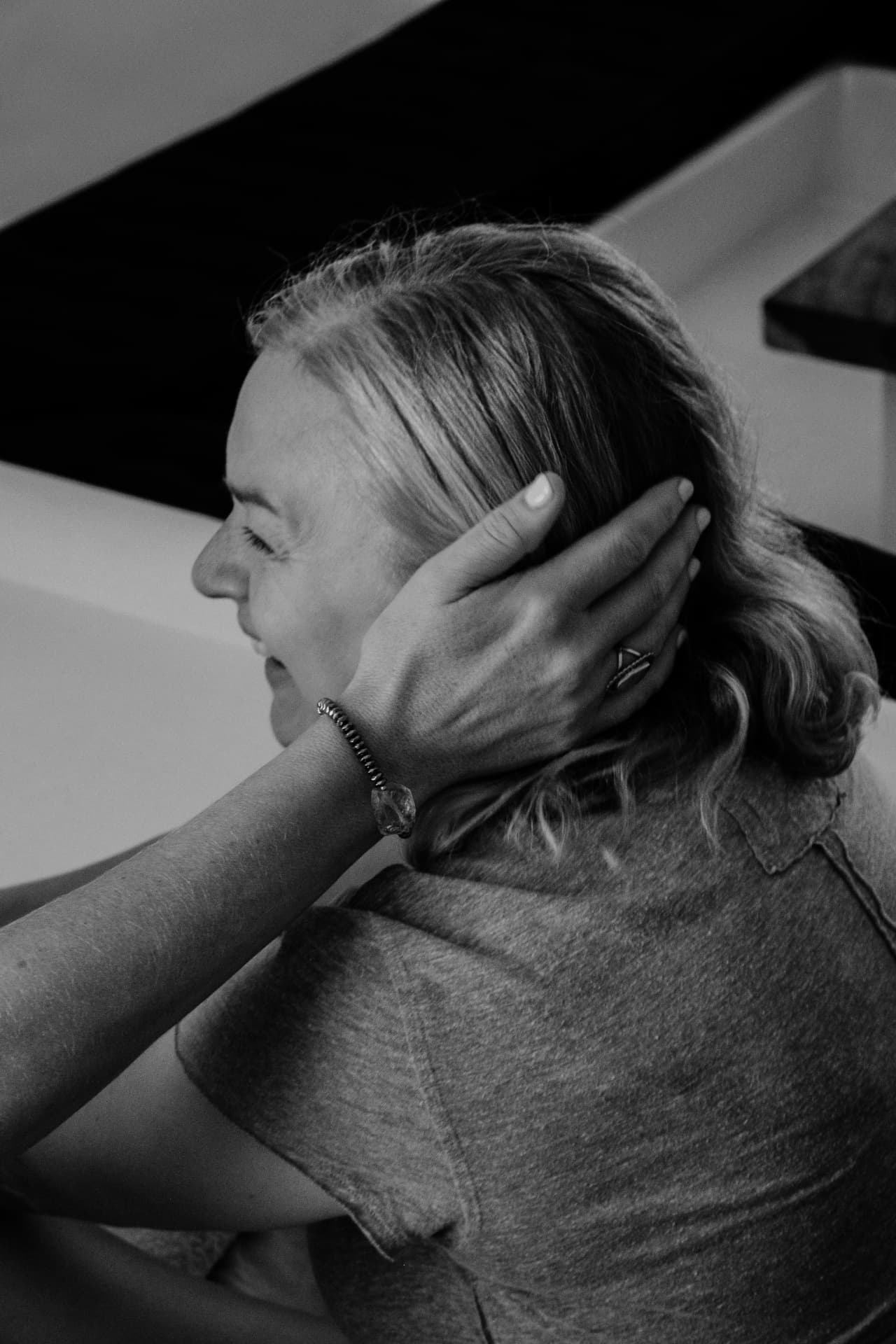 A woman receiving a gentle touch beside her ear, in black and white
