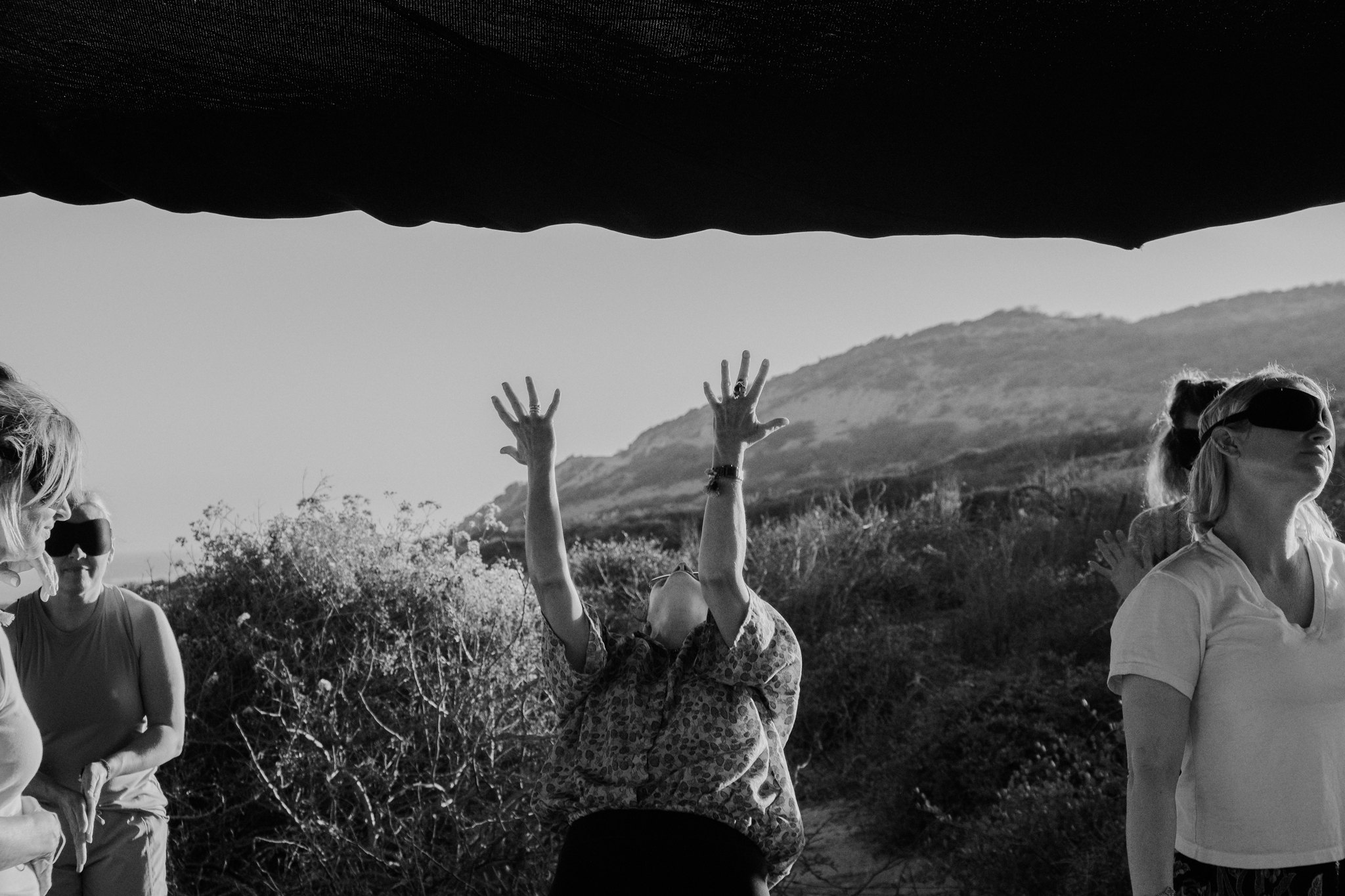 Women dancing with arms raised on an open deck, in black and white