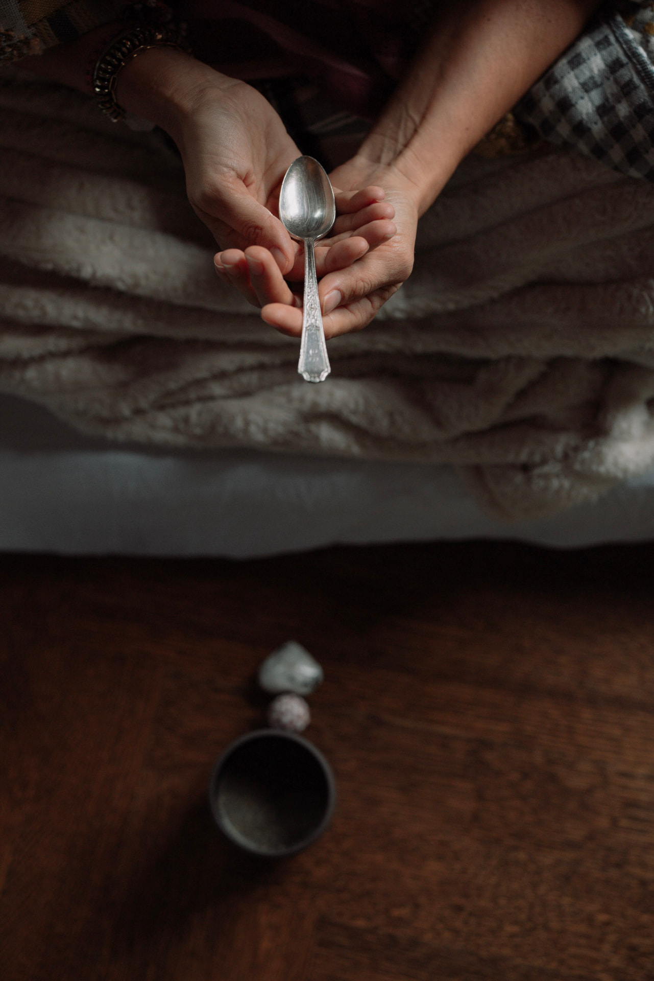 Hands holding a silver spoon in ritual