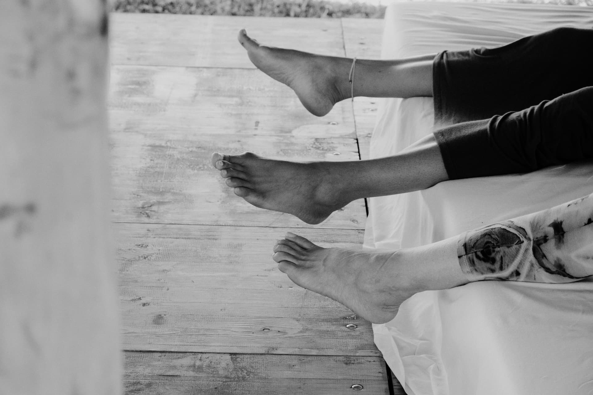 Bare feet raised above white mattresses, in black and white