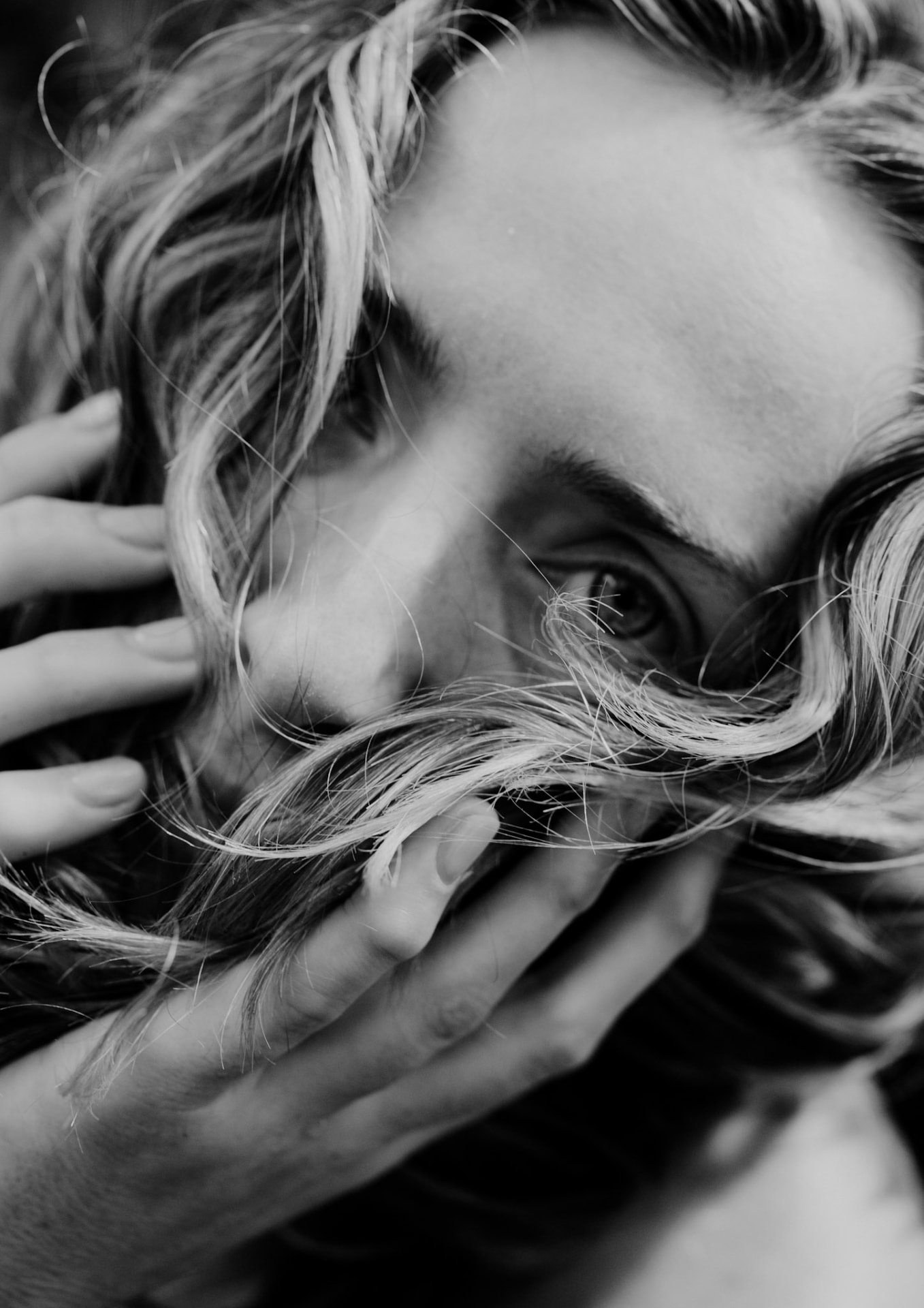 Black and white close-up of a woman with her hands and loose hair framing her face