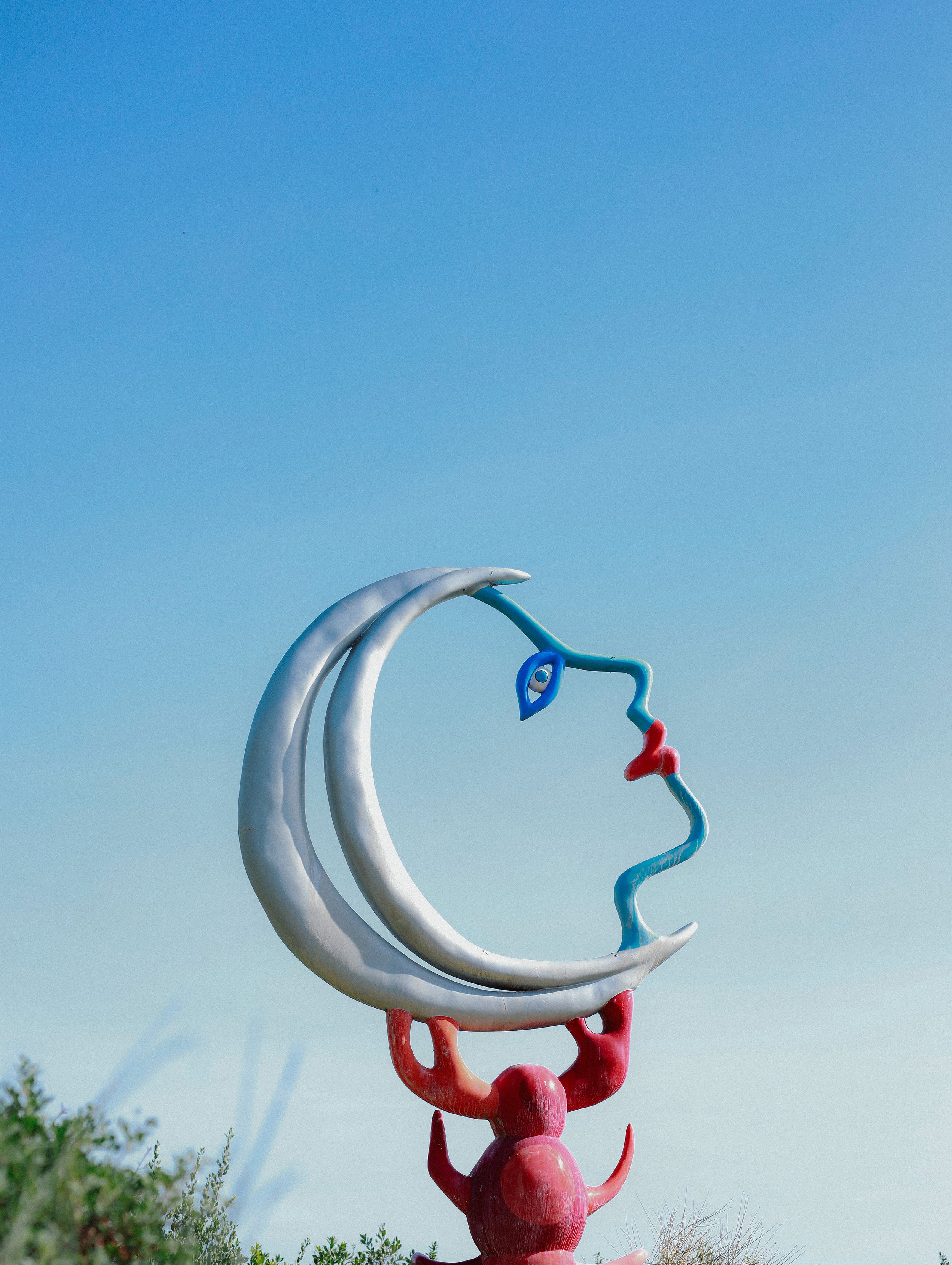 A crescent moon sculpture against the blue sky in the Tarot Garden