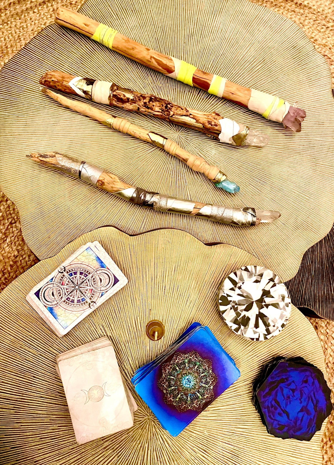 Wrapped staffs, colorful handmade objects and cards arranged on a woven surface