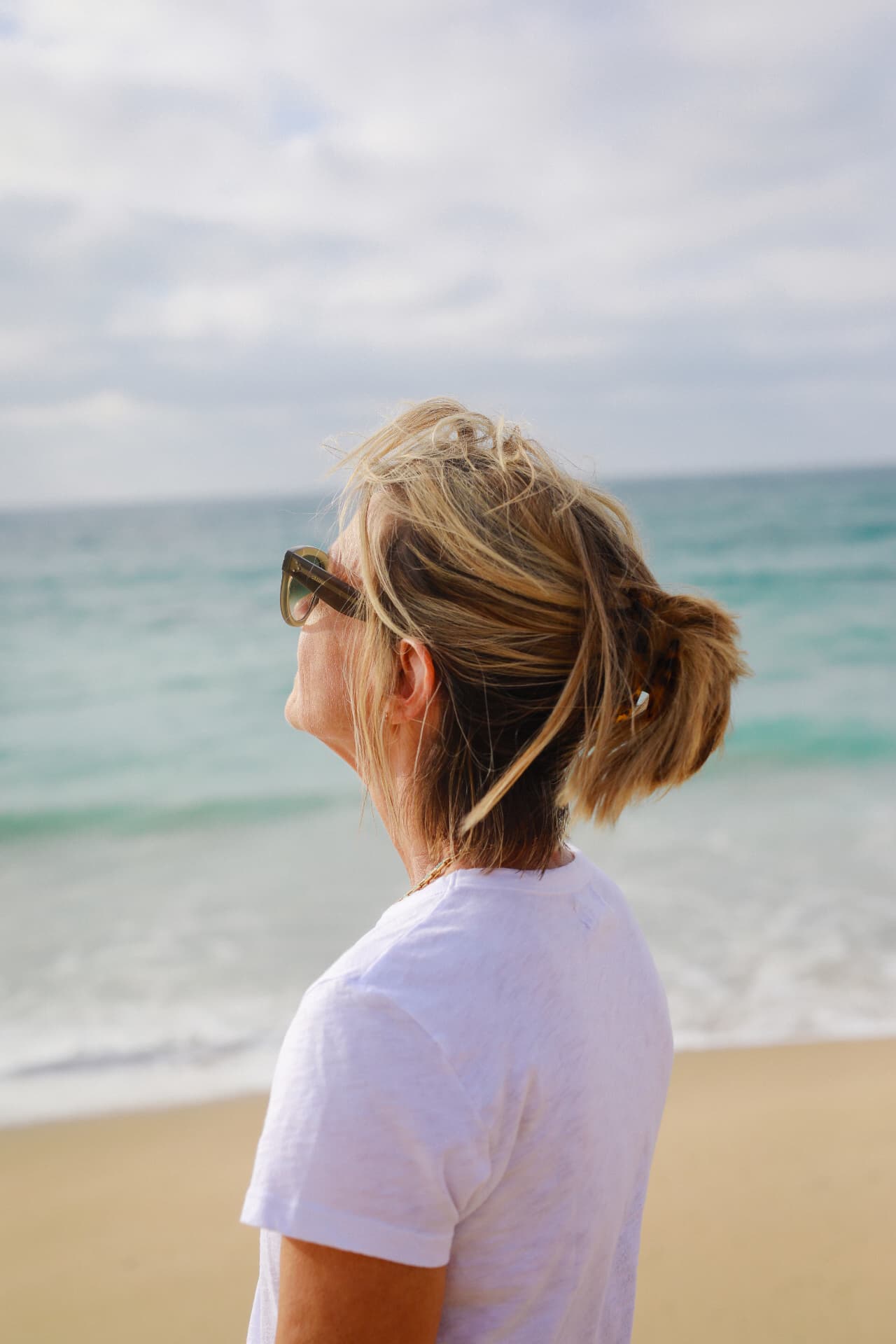 A woman in sunglasses looking out toward the sea